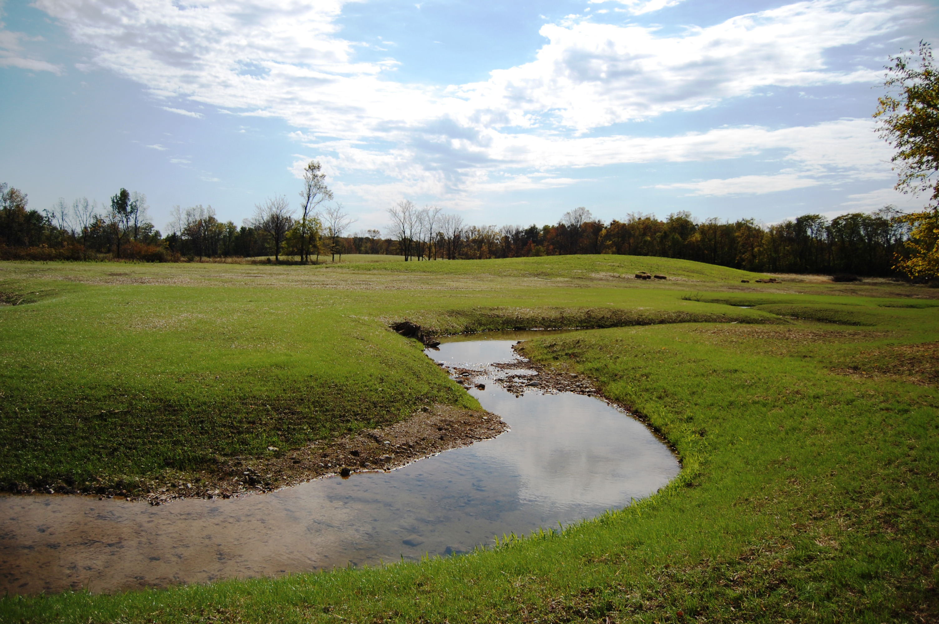 A meandering stream between grassy hills.