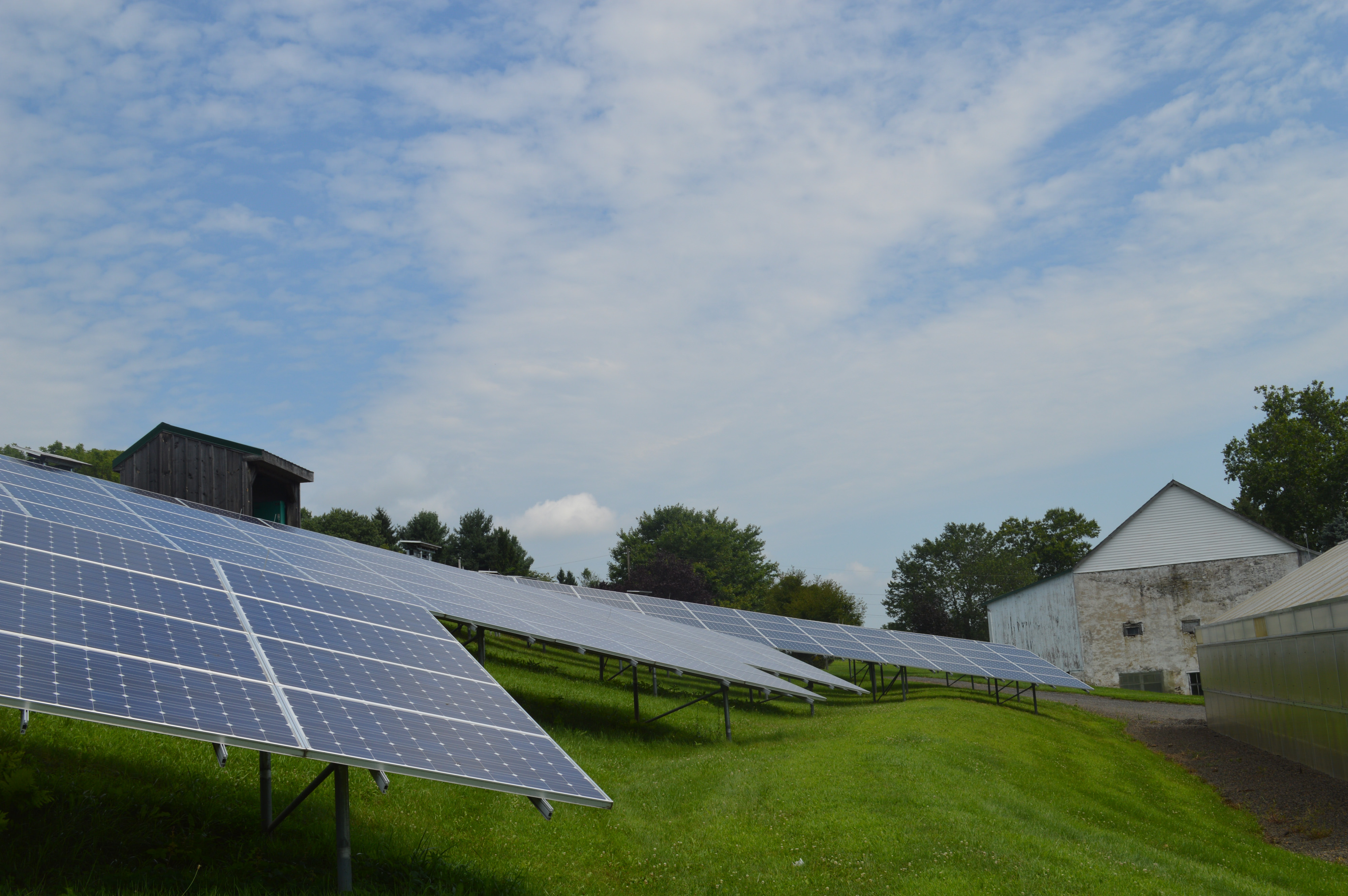 Solar panels on grassy foreground, barn in background.