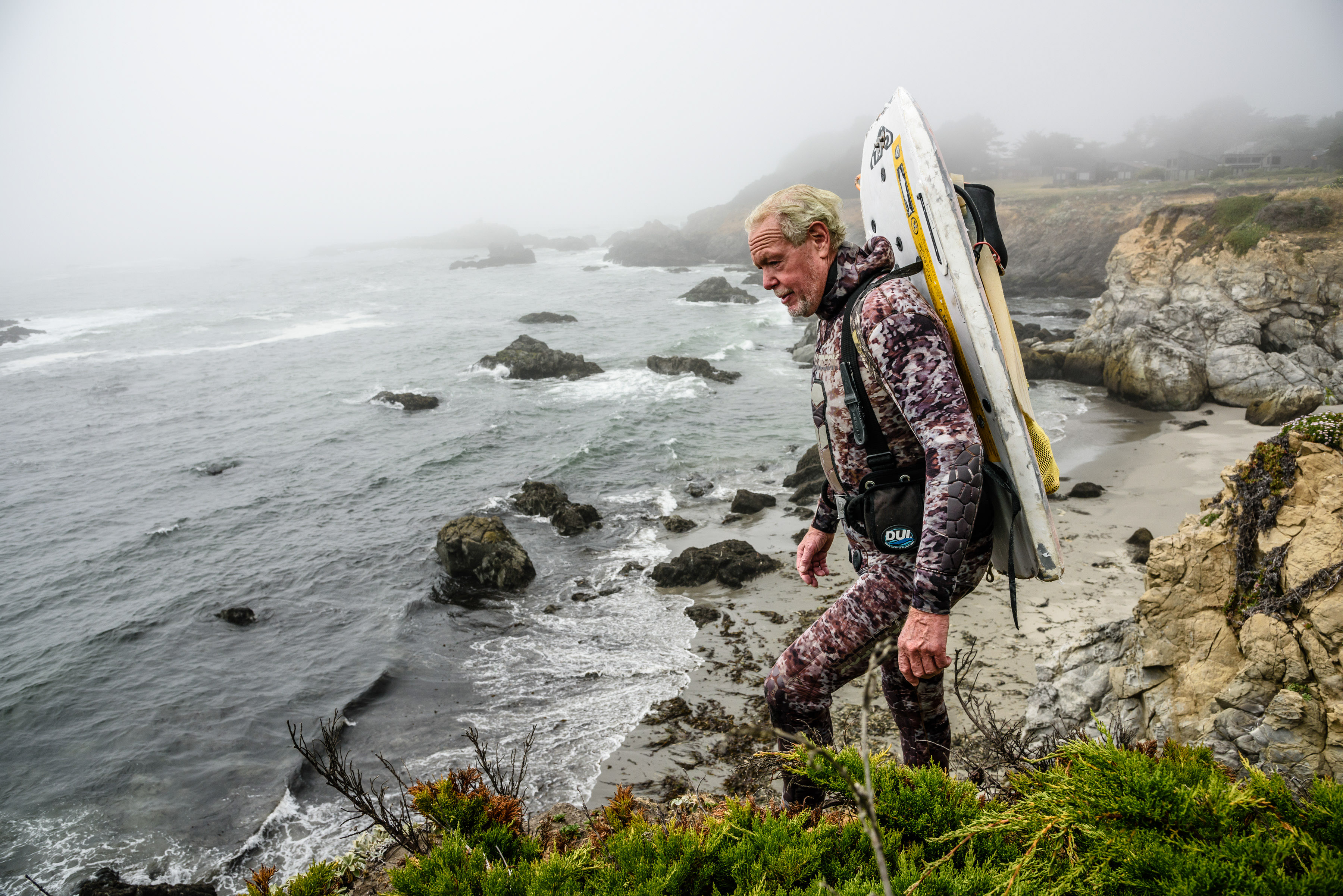 Red abalone diver and TNC partner Jack Likins walks along the ocean's rocky shore before a dive off Mendocino County.