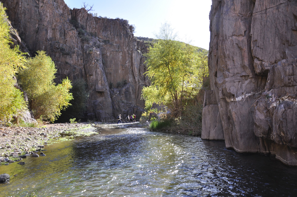 A river runs through a canyon. Hikers in the background.