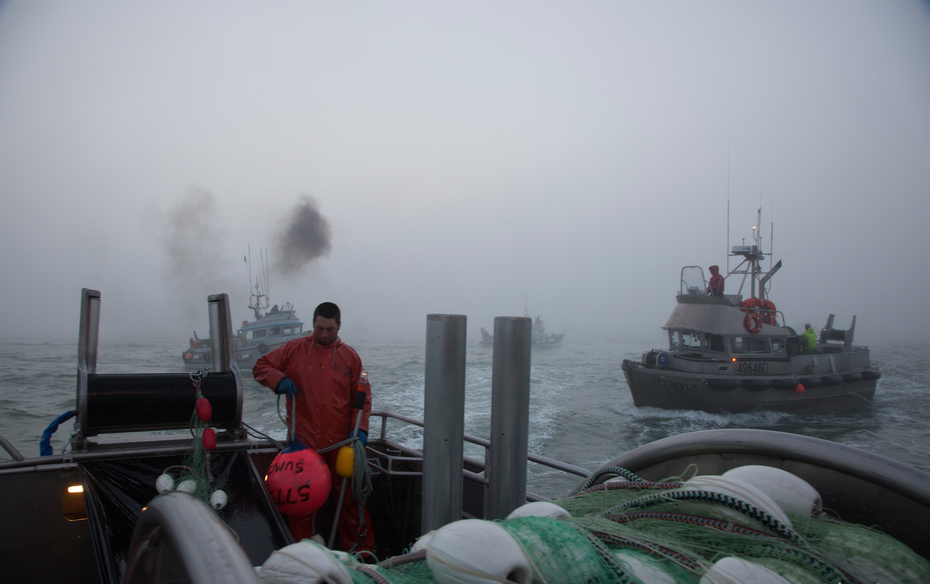 Commercial drift boats gather in one location and people onboard prepare to begin fishing in Bristol Bay.