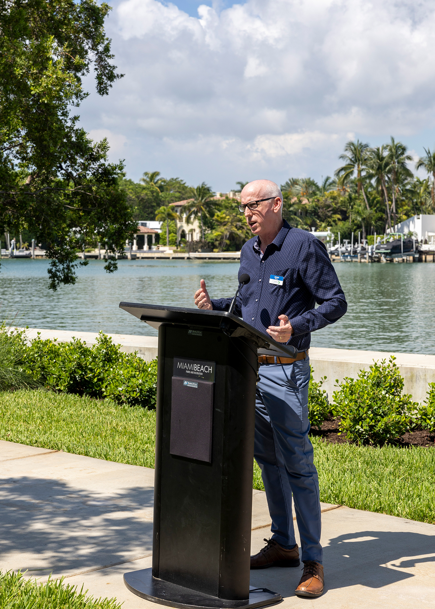A man stands behind a podium and speaks at the Brittany Bay Living Shoreline.