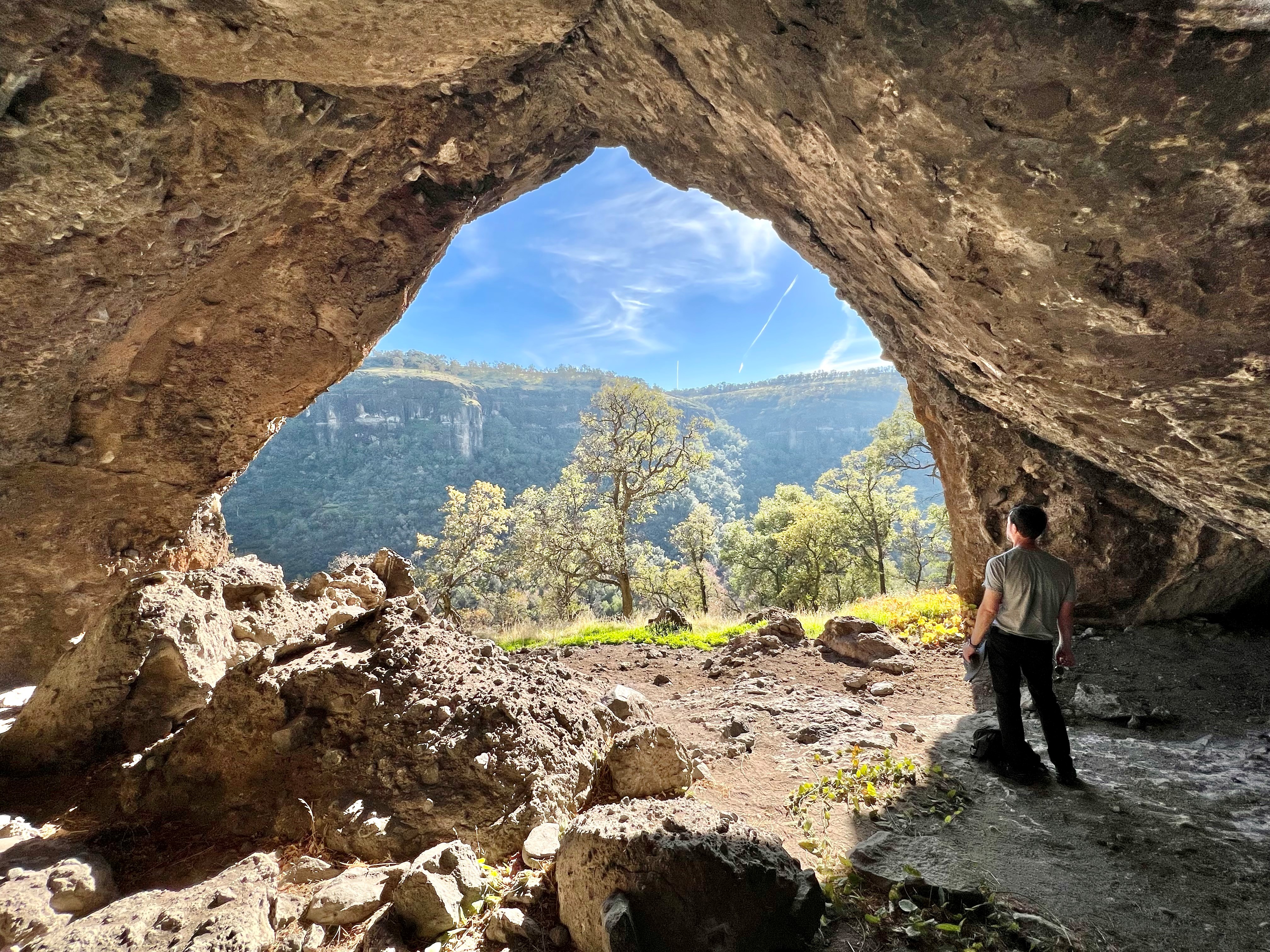 A person stands under a rock overhang on Dye Creek.