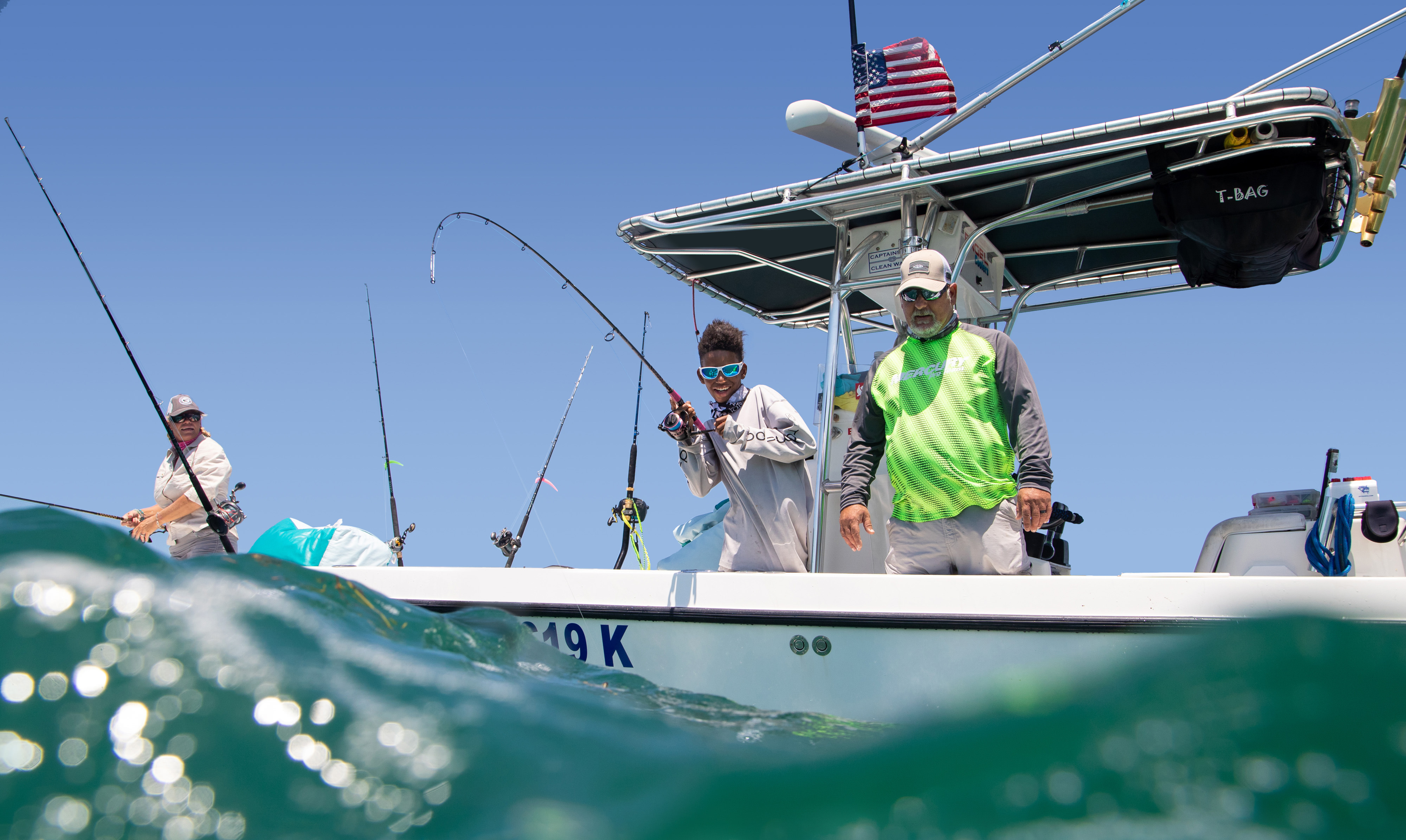 Three fisherman on a small boat with fishing lines in the water in Key Largo, Florida. 