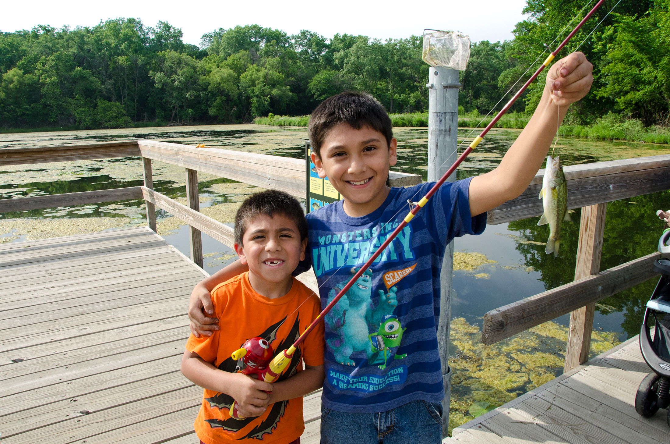 Two young boys hold up their catch from a fishing pier.