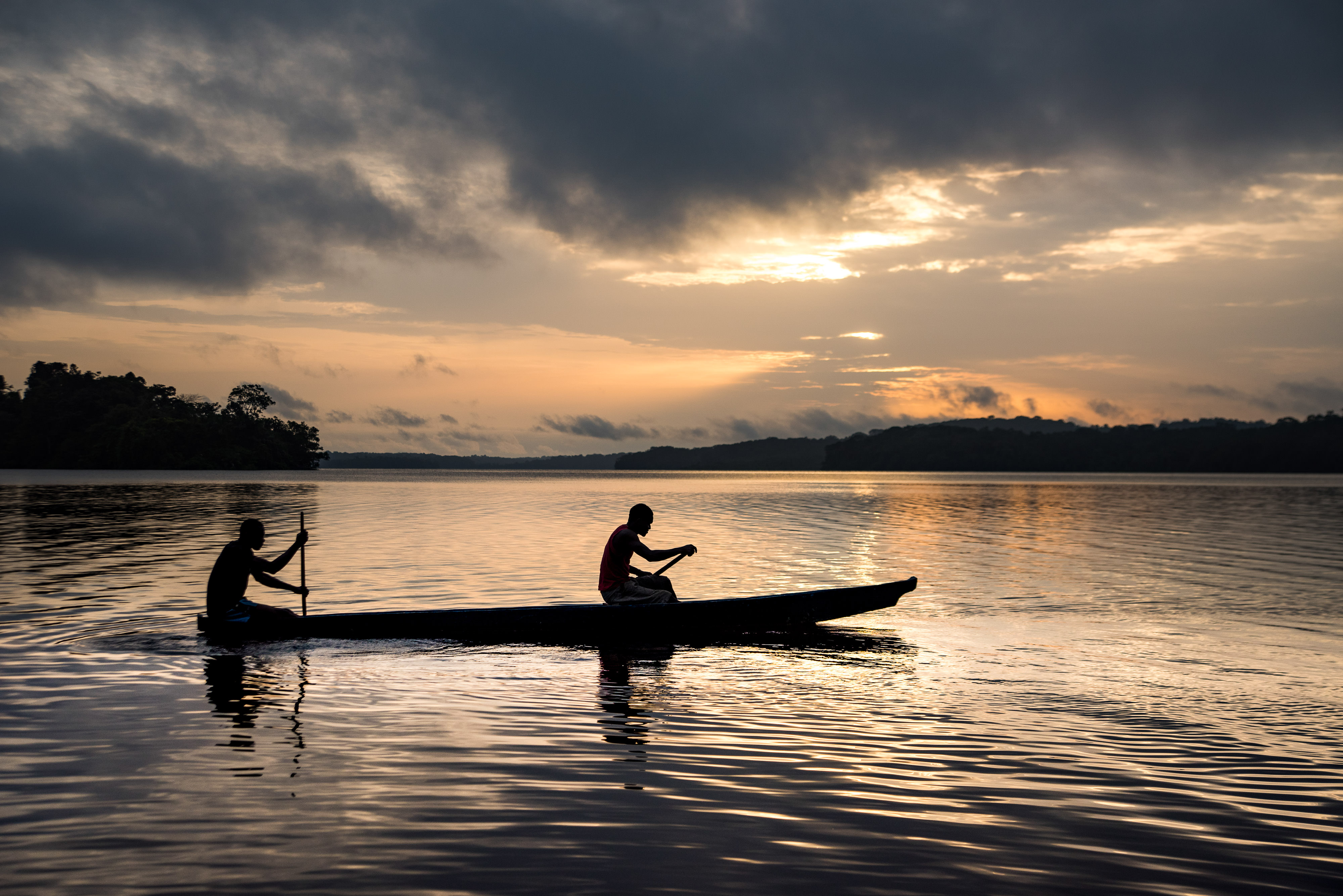 Two fishermen in a canoe at sunrise