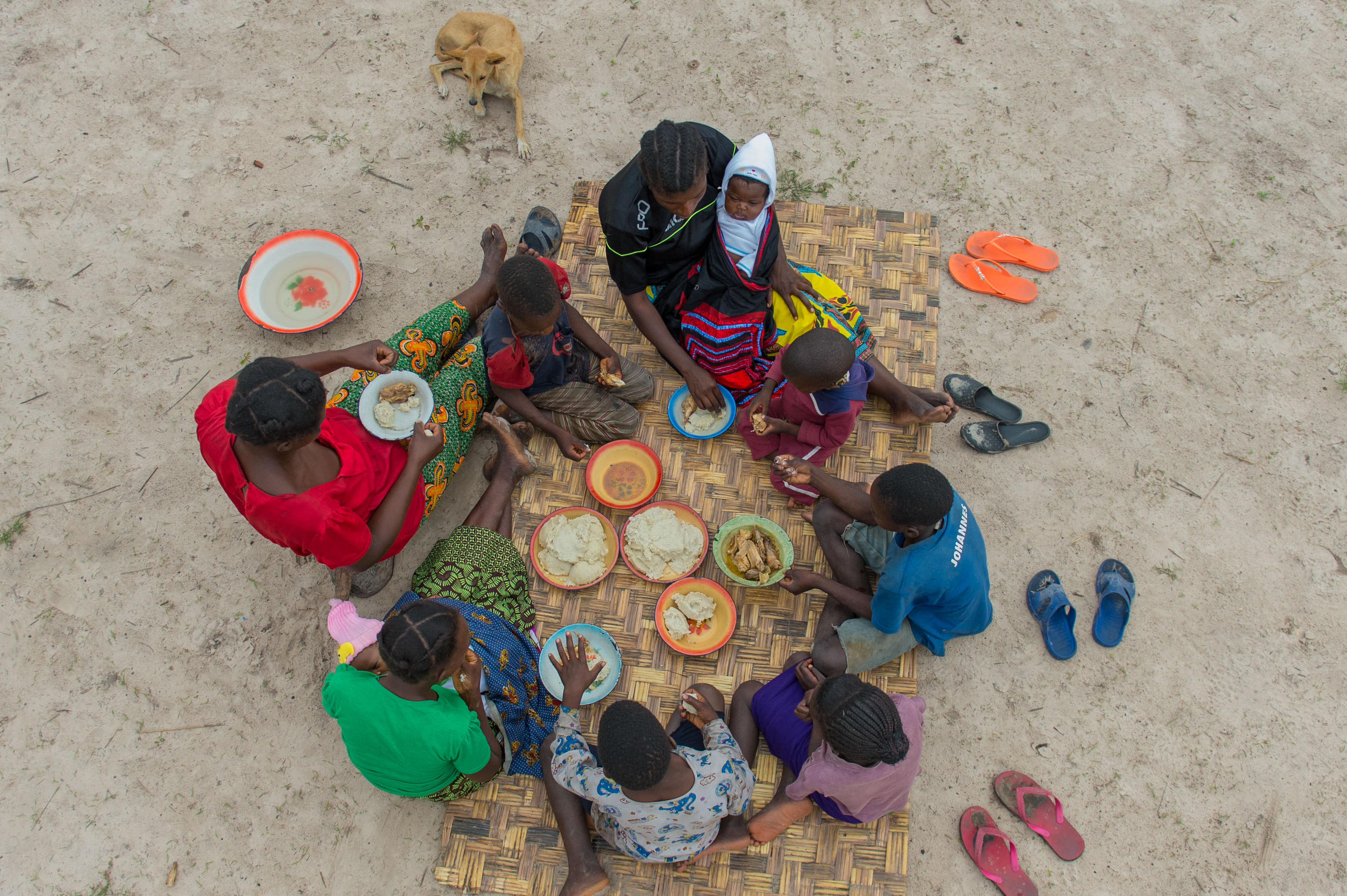 Family eating a meal on a mat on ground