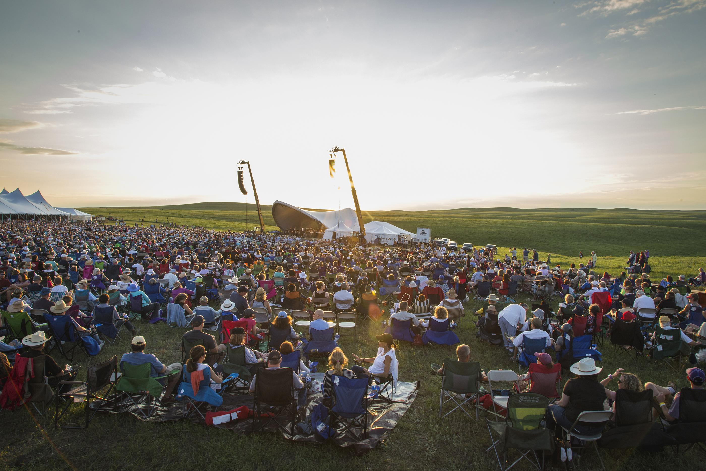 A crowd listens to a sunset performance 