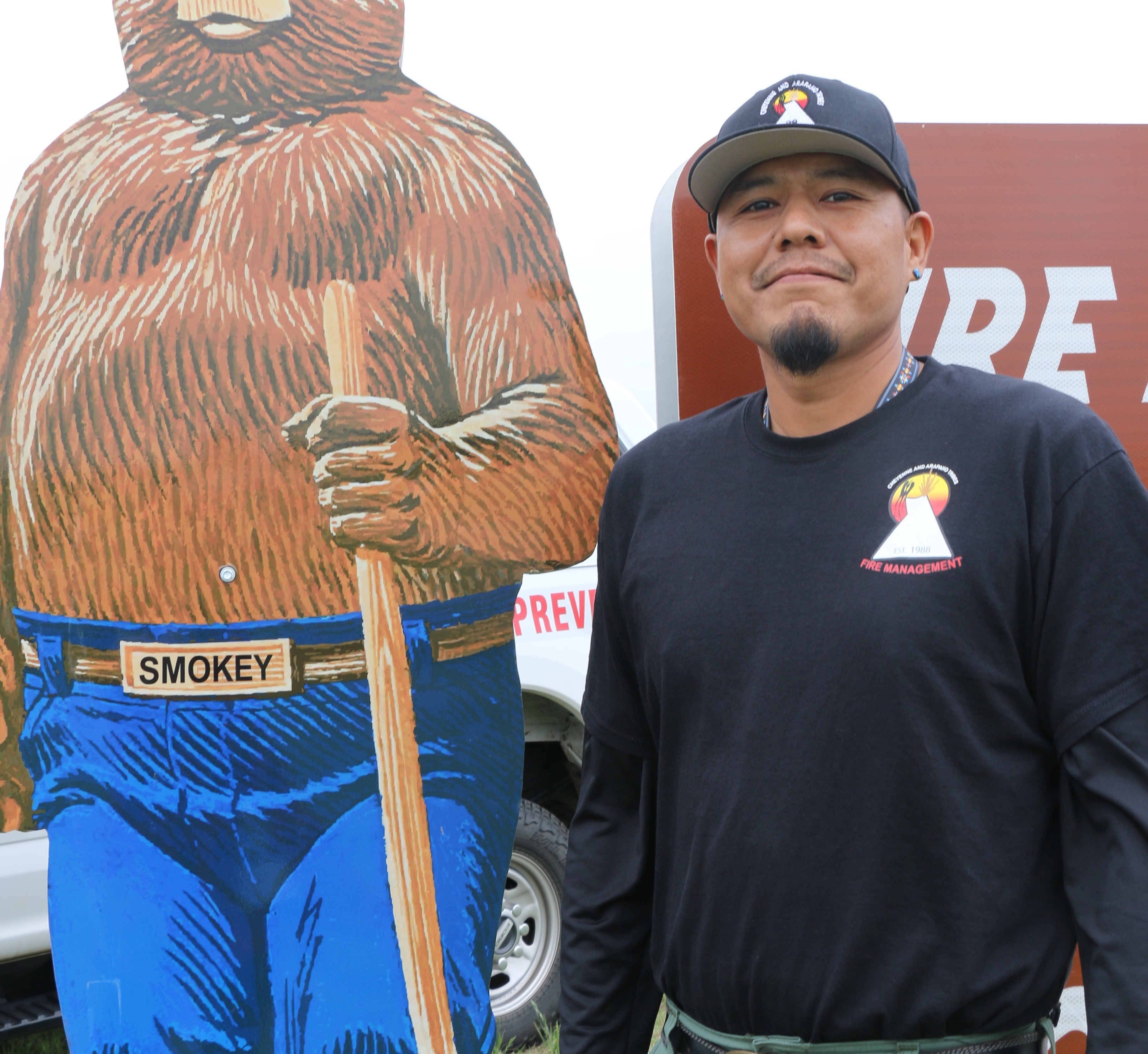 Man standing next to Smokey Bear.