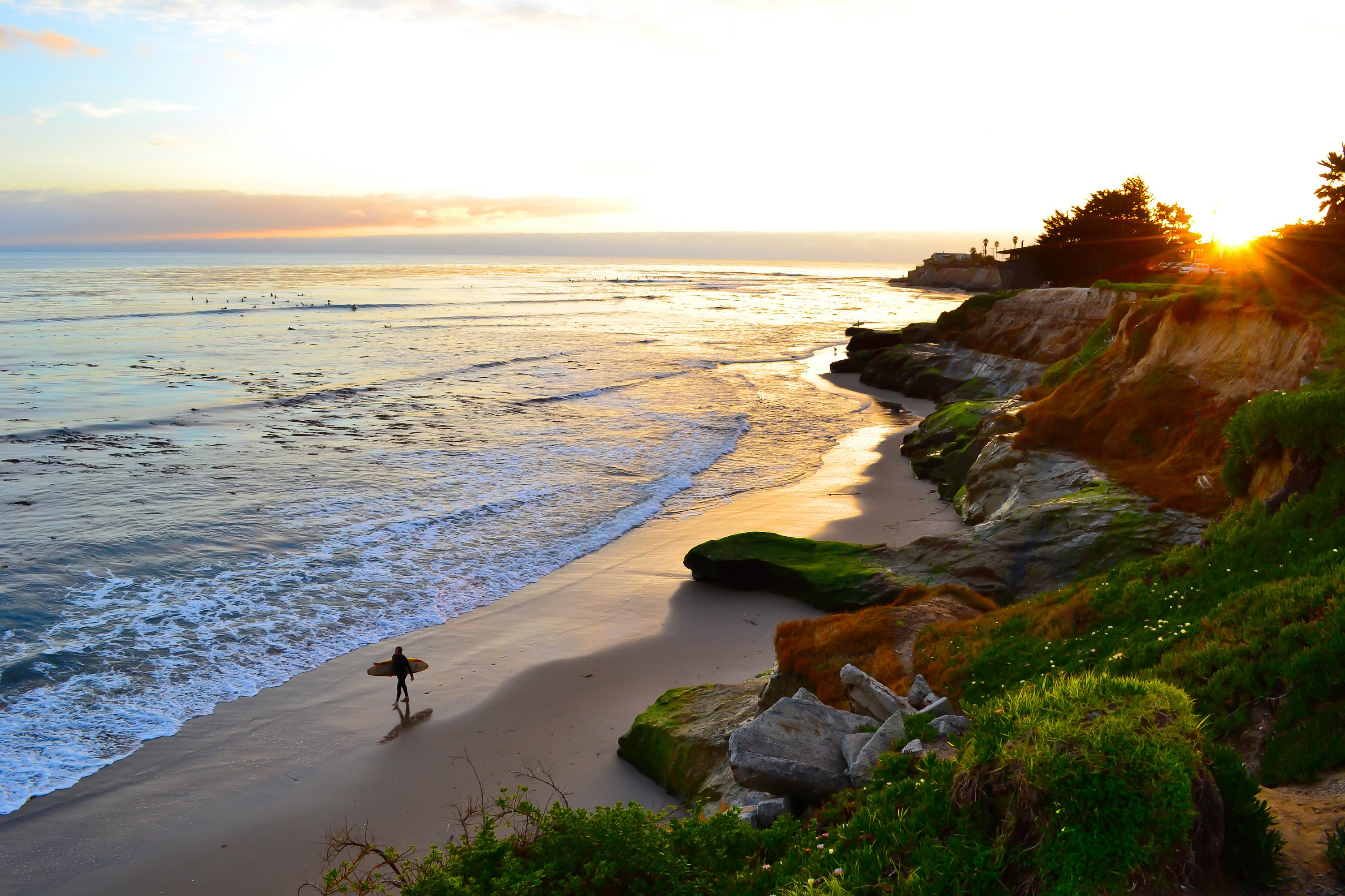 Surfer walking along the beach in Santa Cruz.