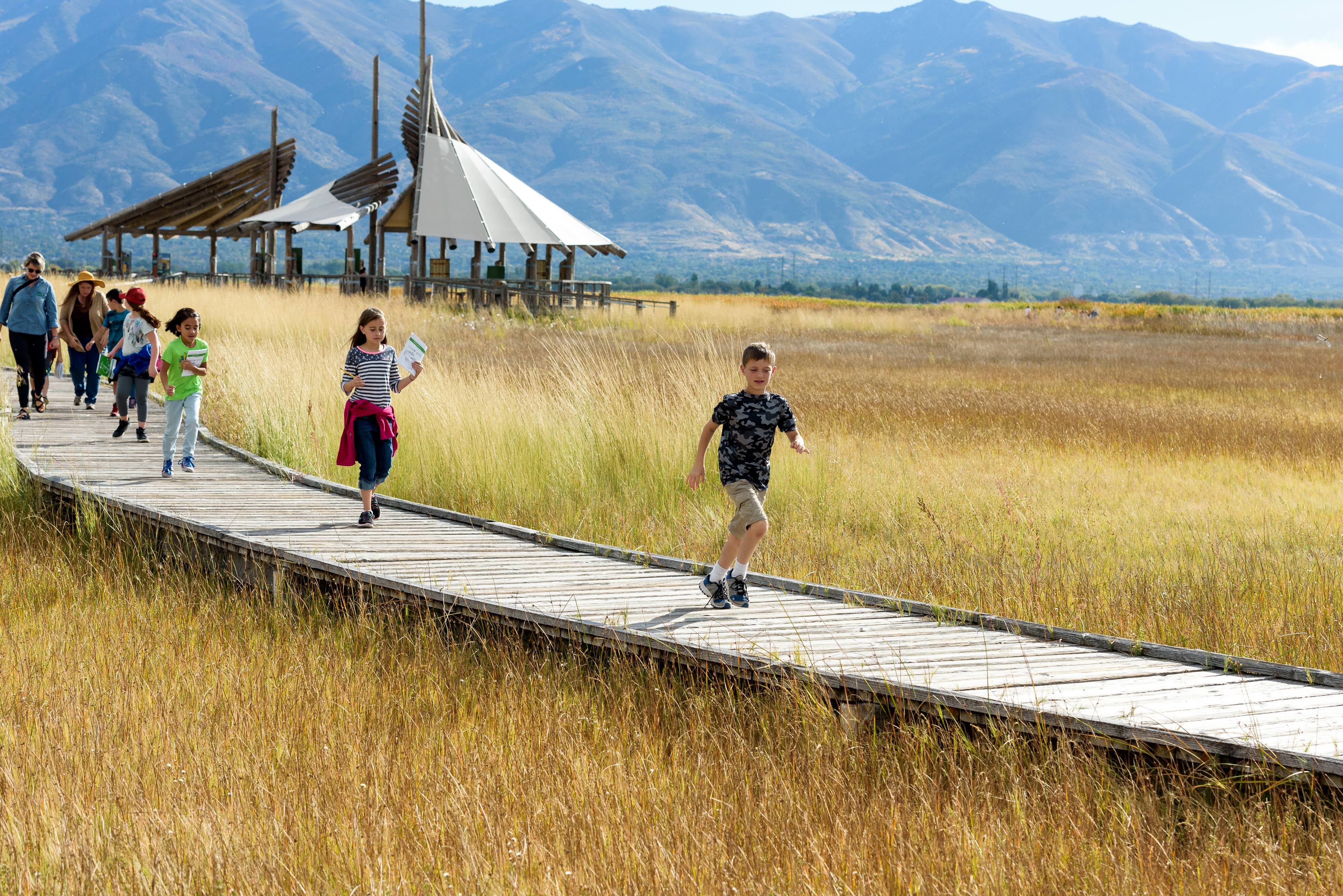 A group of kids running on a boardwalk.
