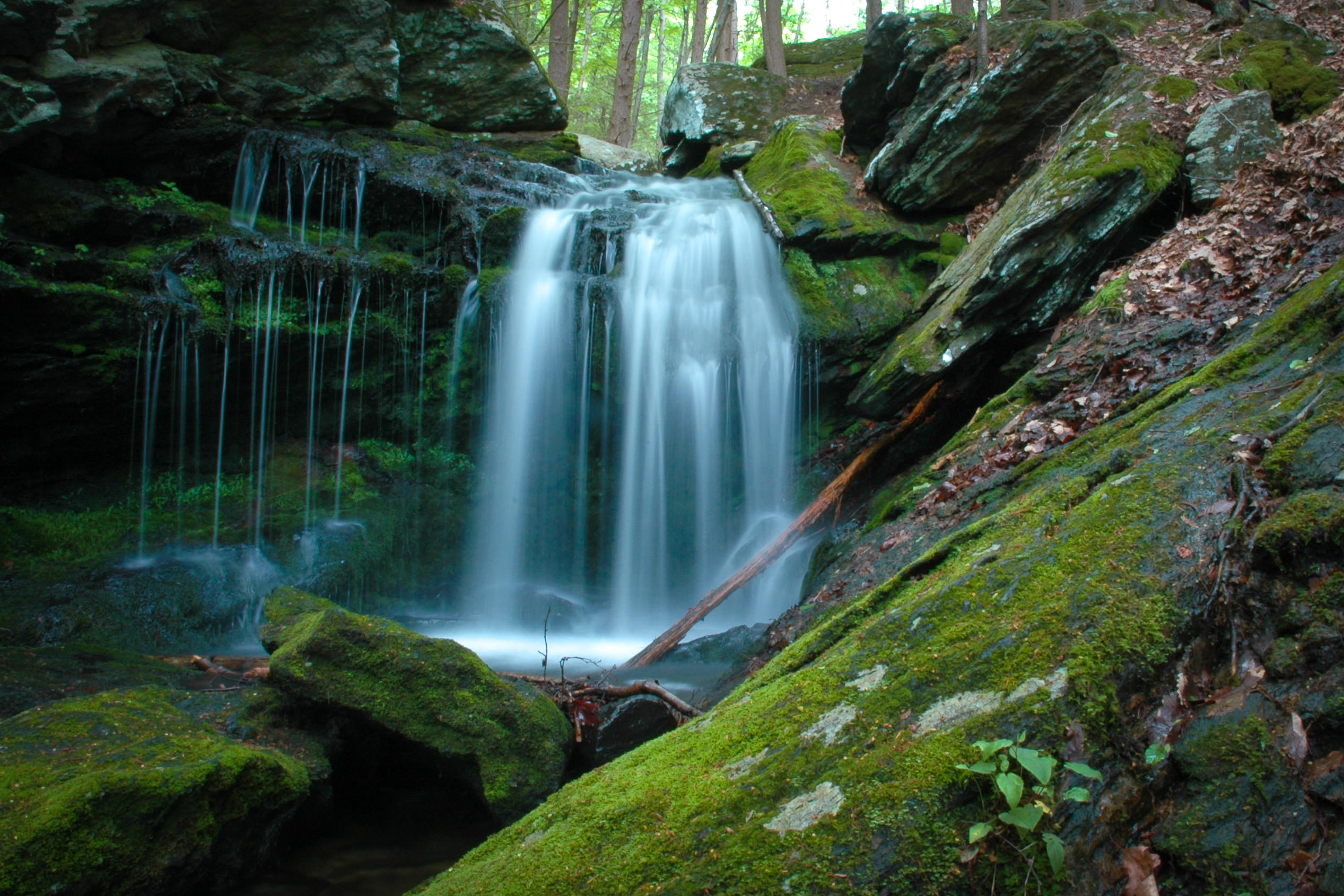 A waterfall pours over large rocks.