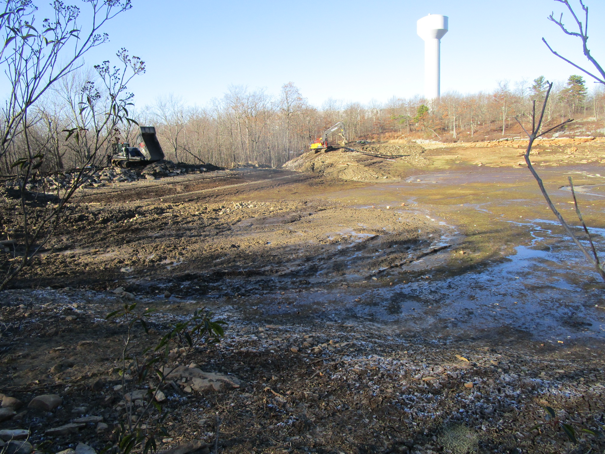 A muddy field with a water tower in the background.