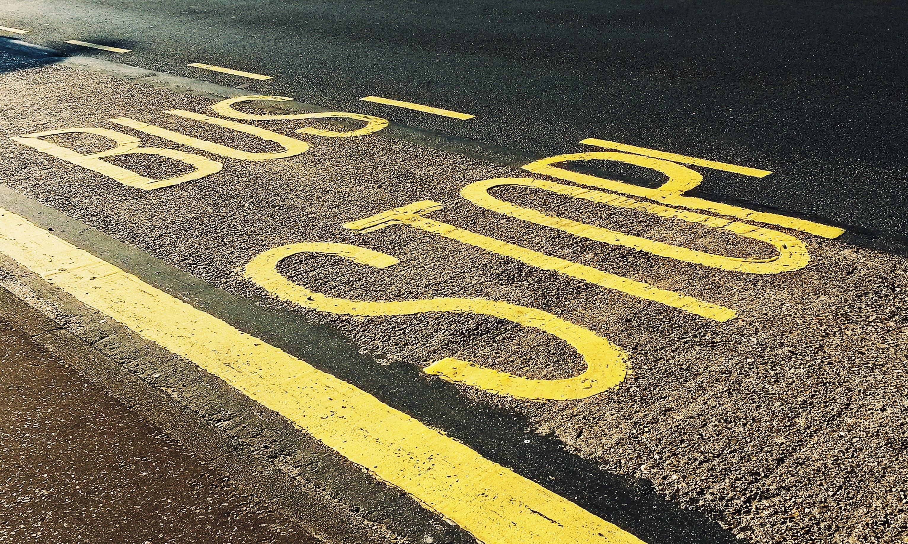 A road with the words Bus Stop painted on it in yellow.