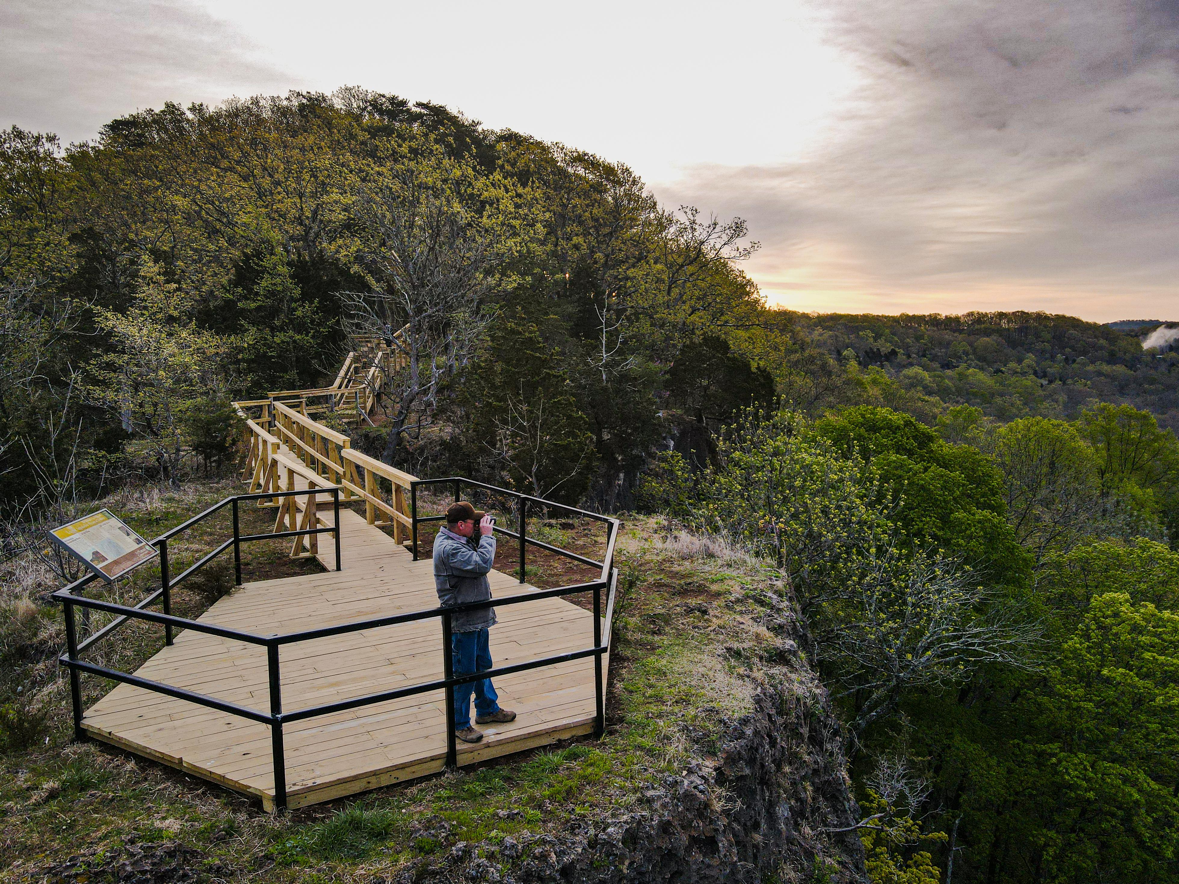 A drone shot of an adult on the overlook platform at the peak of Buzzardroot Rock.