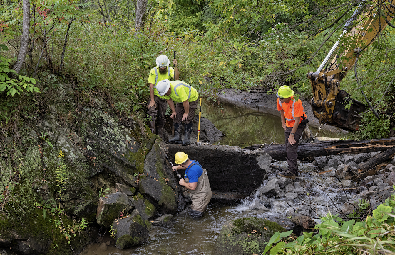 Three people removing a dam.