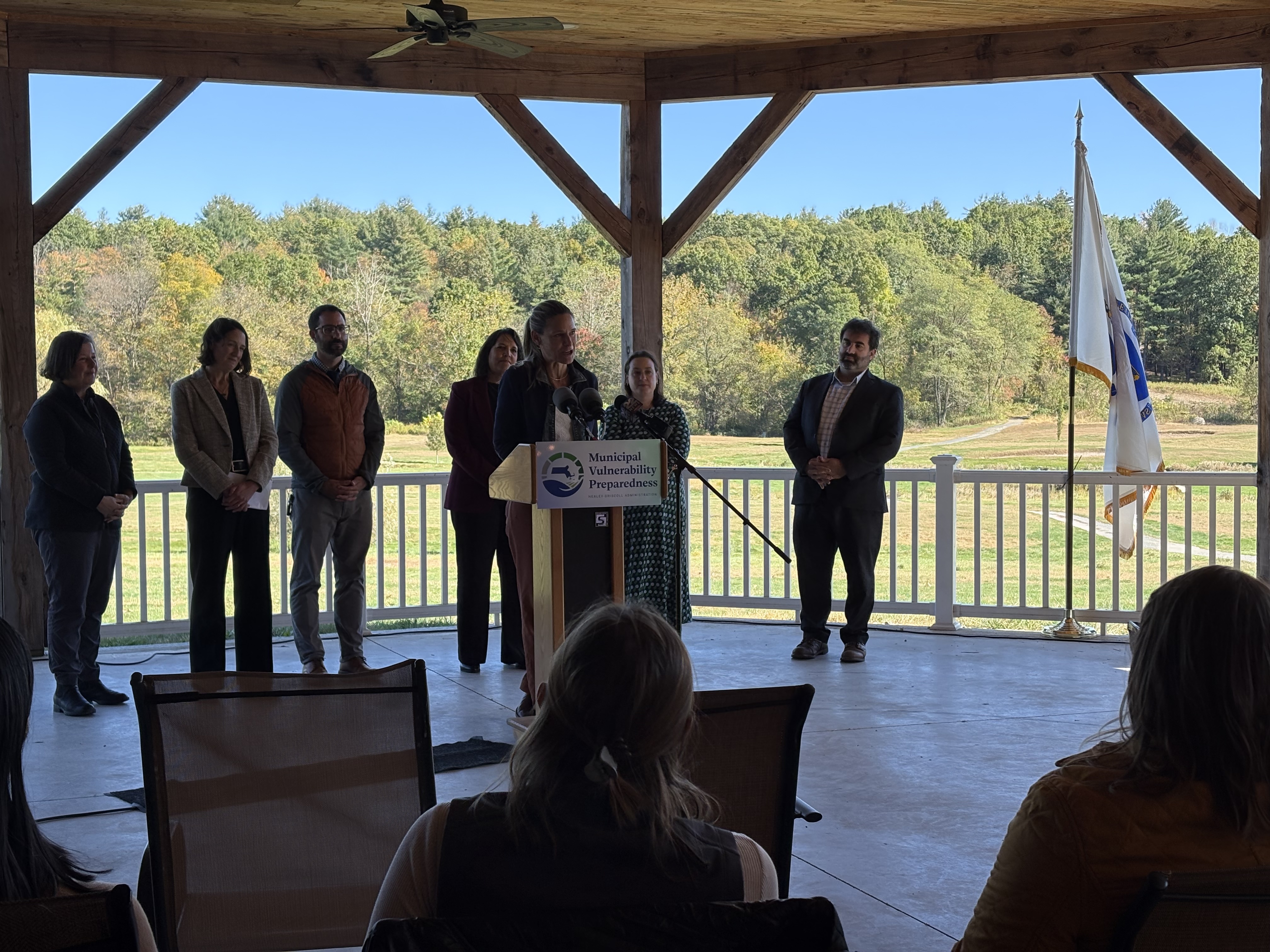 Speakers gather at a podium for a grant celebration. 