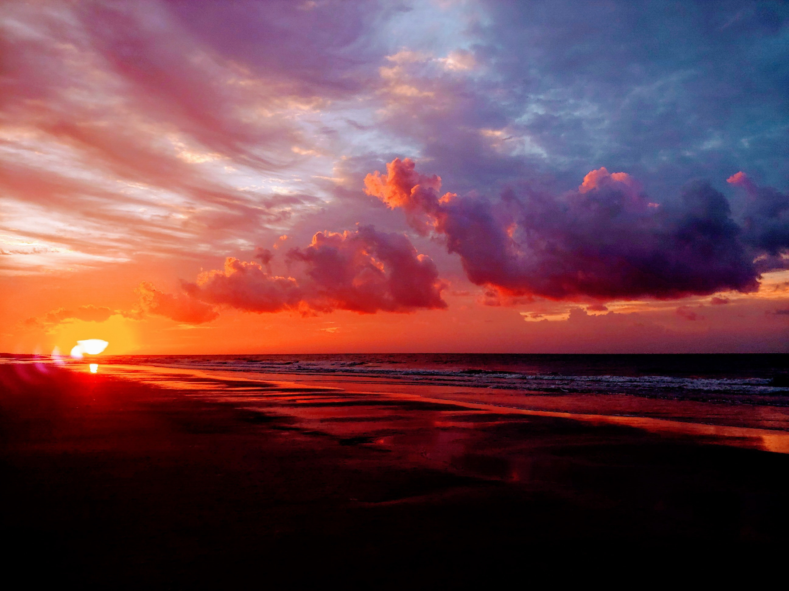 Sunrise over the ocean and a flat sandy beach