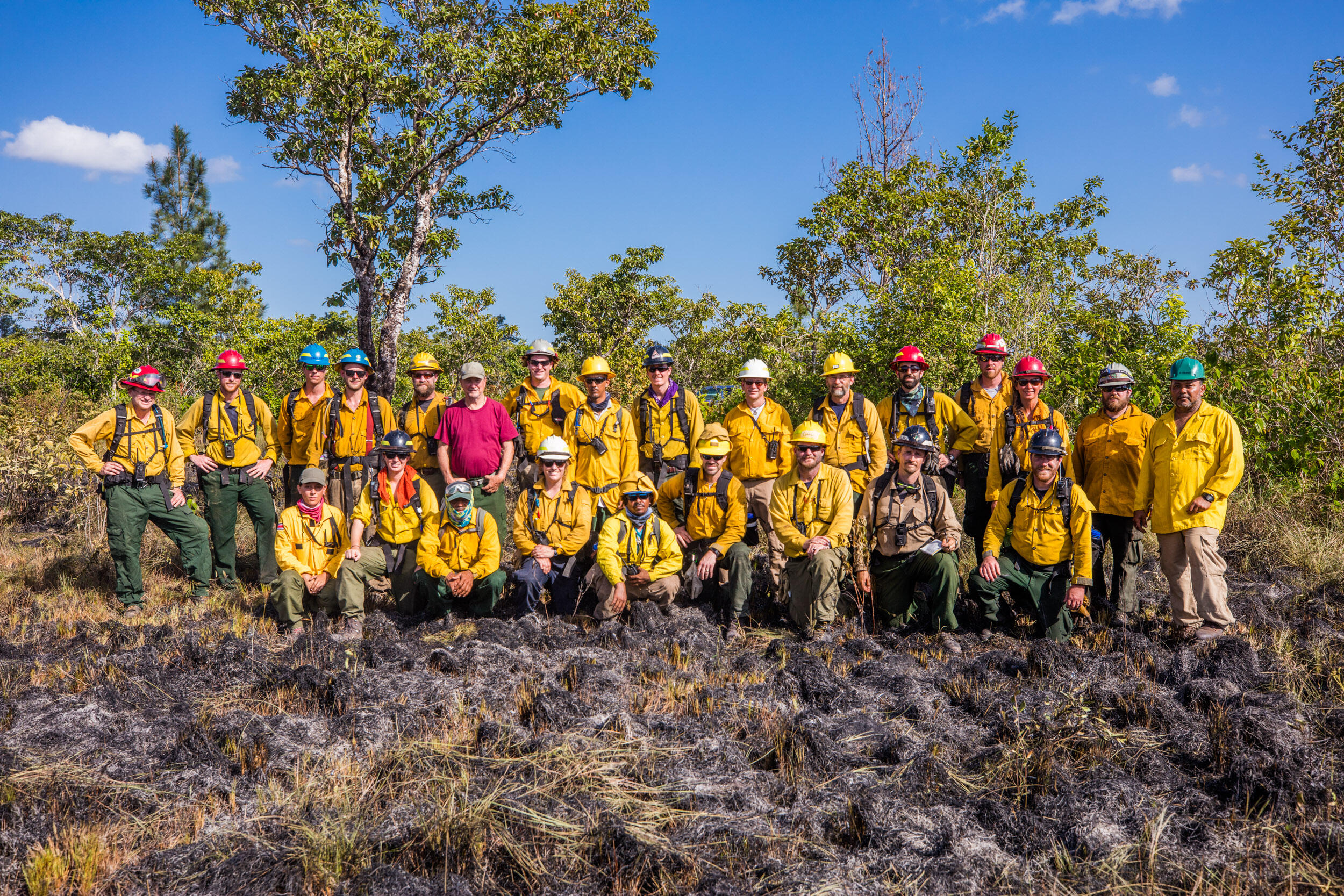 Nearly 30 fire practitioners stand together and pose for a group photo in Belize, following a prescribed fire training exercise.