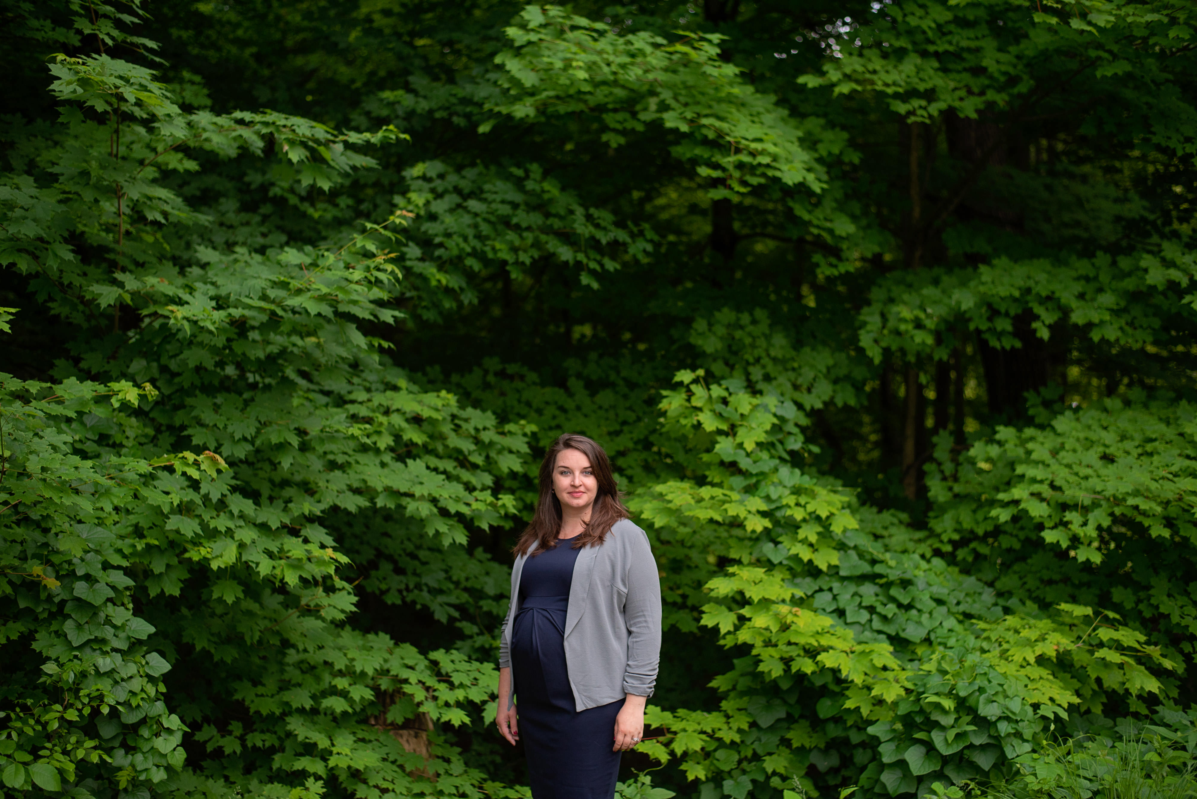 A portrait of a woman in front of green leafy trees.