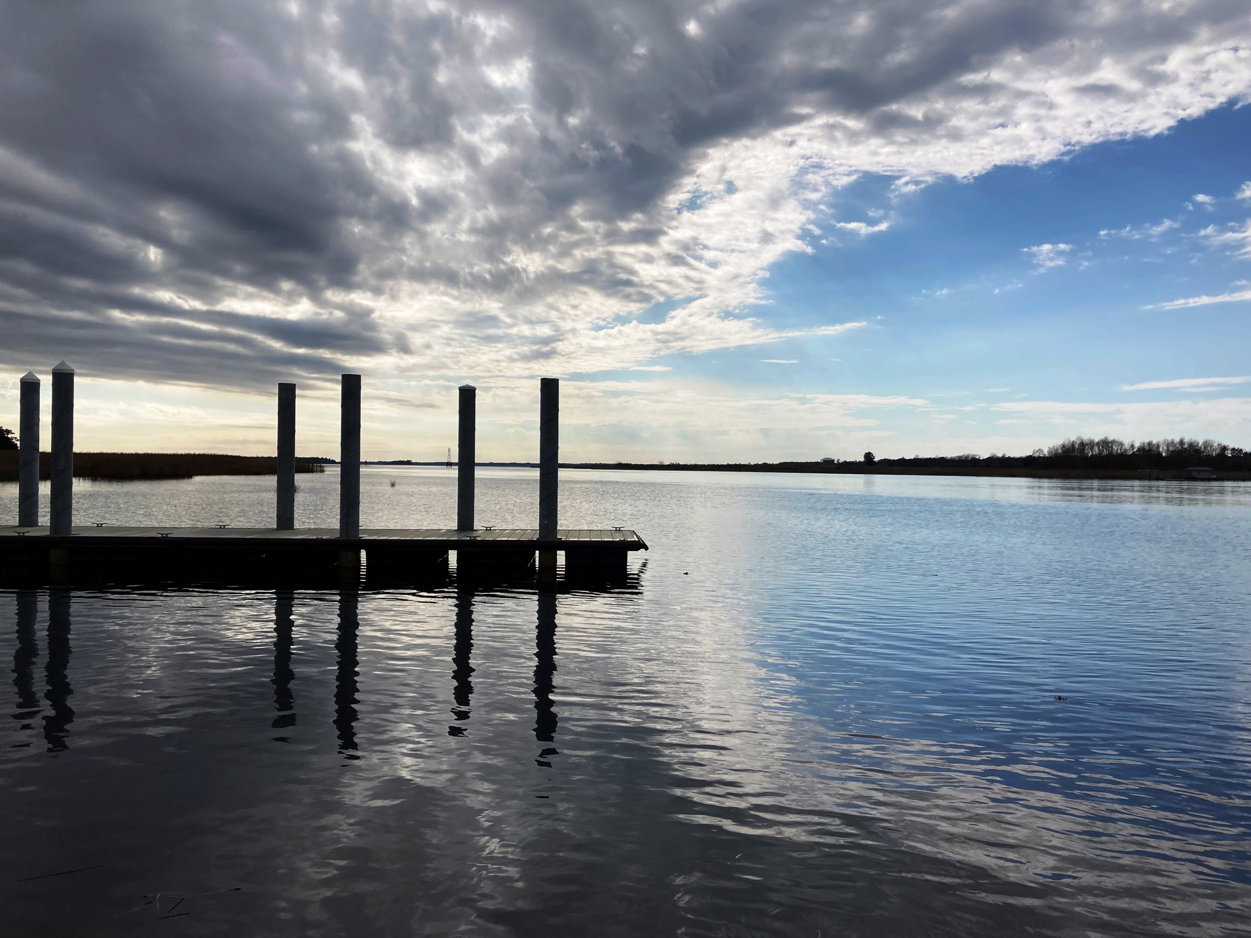 Calm waters surround a dock under a cloudy sky.