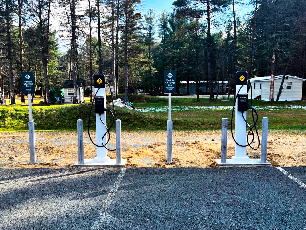 A white car sits in a lot plugged into an electric charging station.