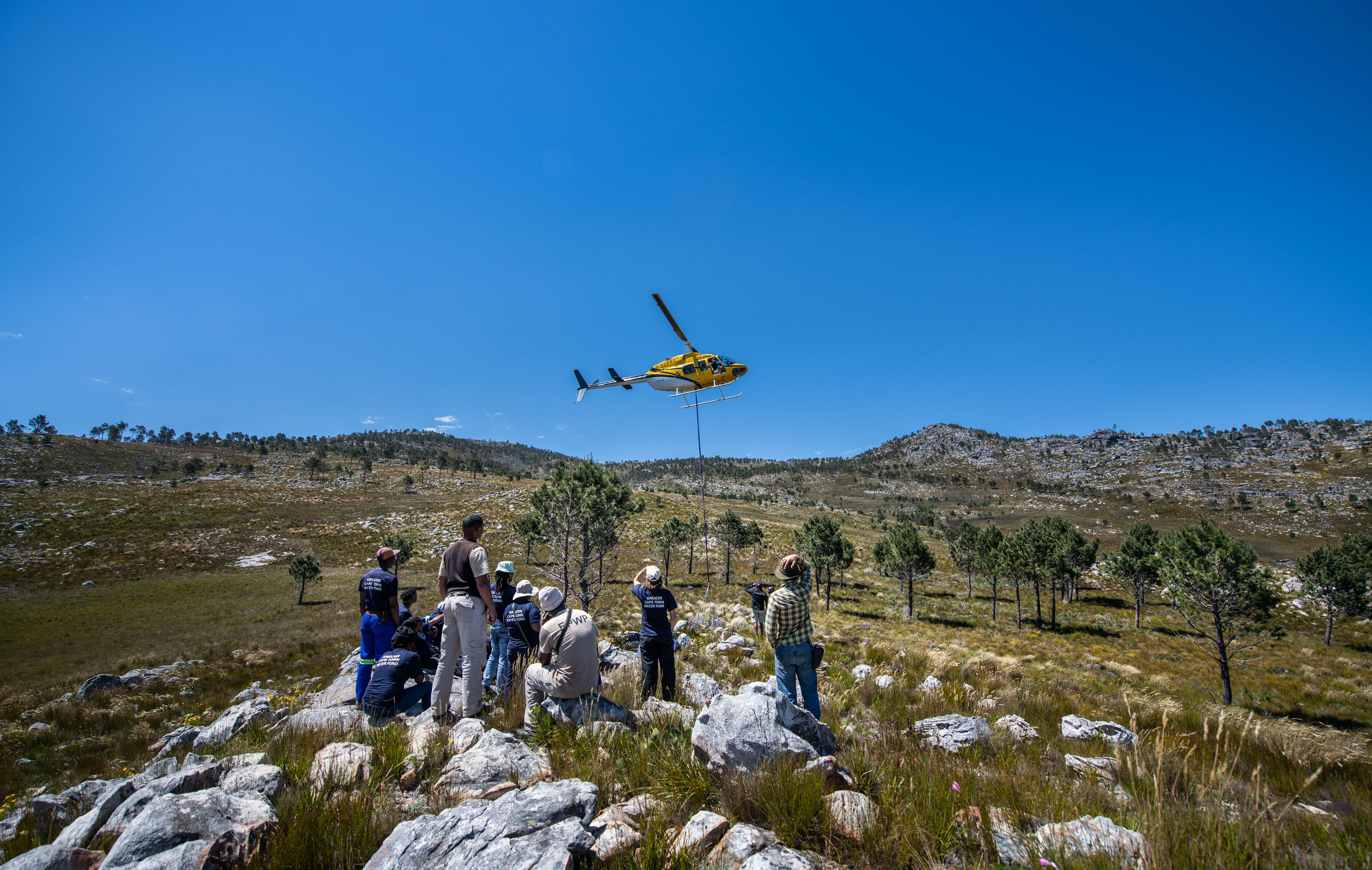 People looking at a yellow helicopter