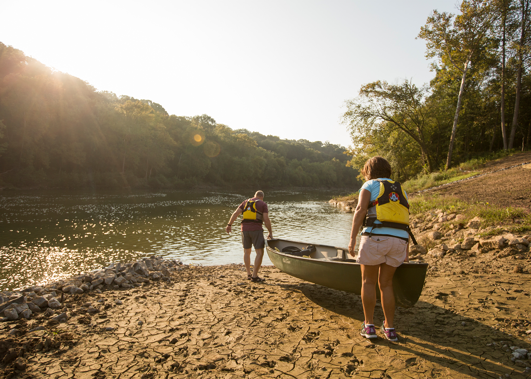 Two people put their canoe in the water on the Green River's muddy banks. 