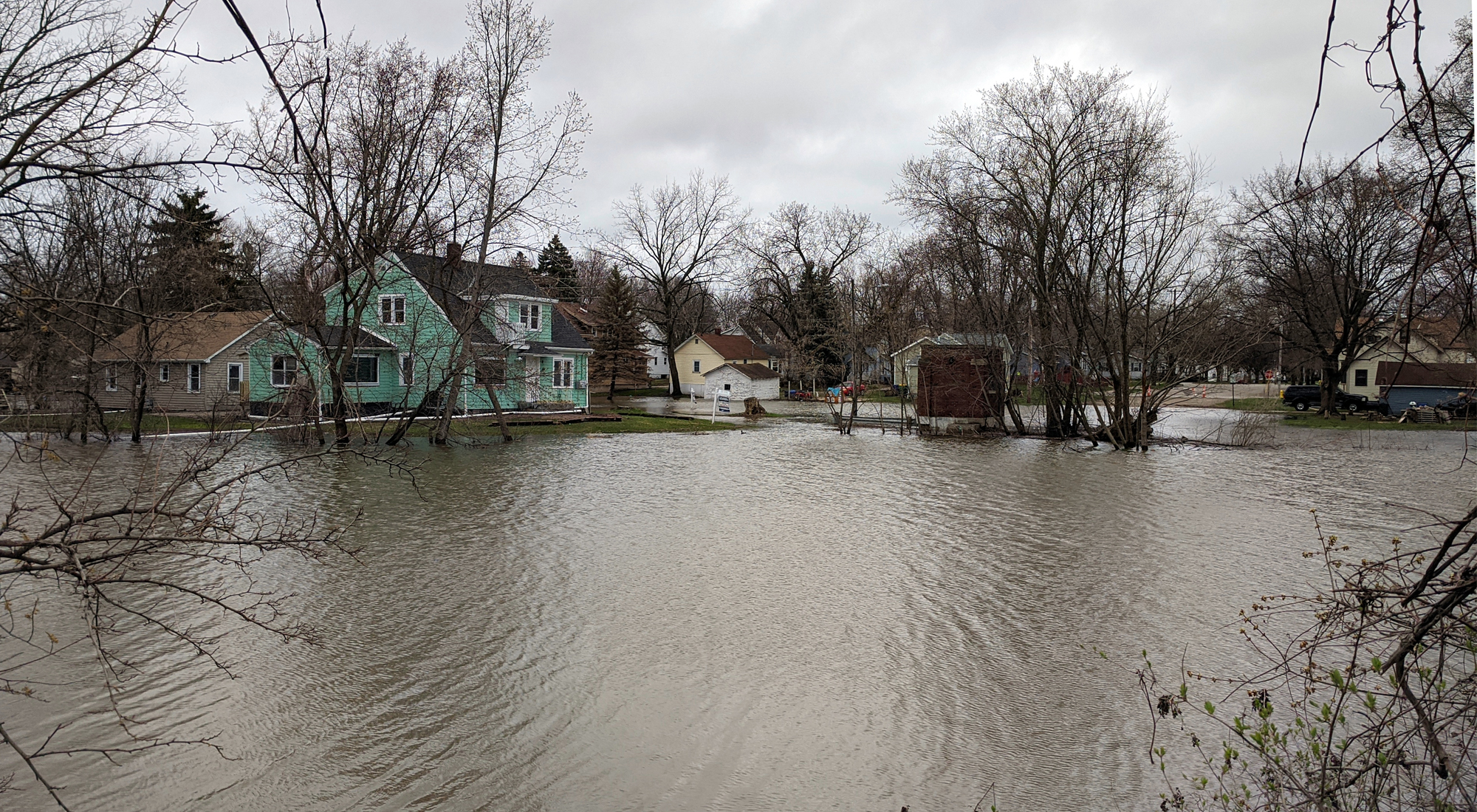 View of homes with a large area of flooding in the foreground.