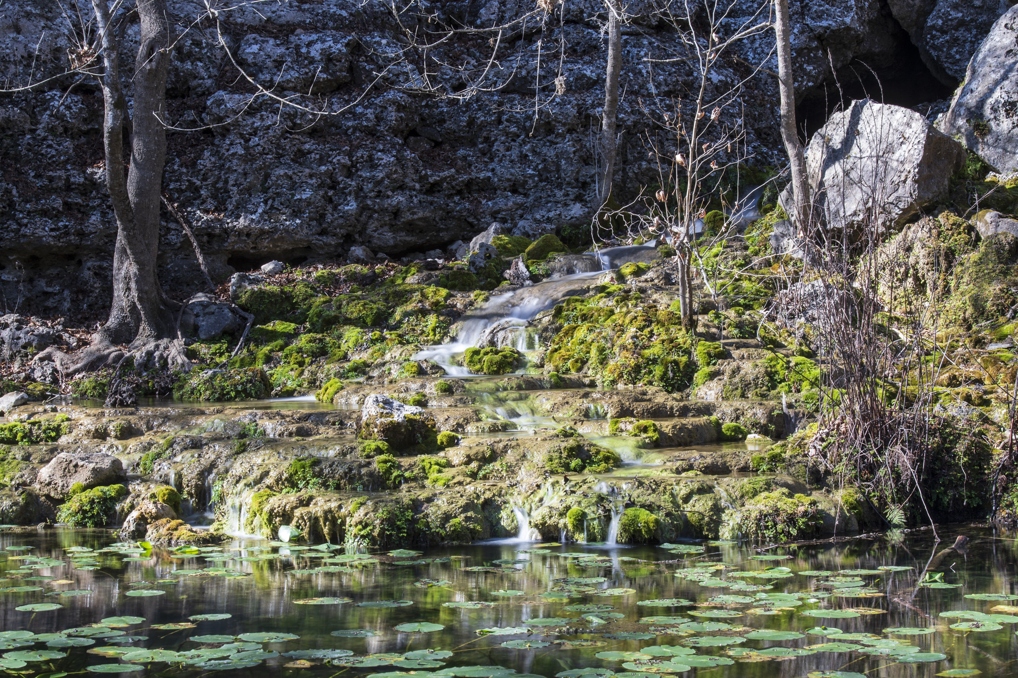 Water falls over stacked rocks into a creek.