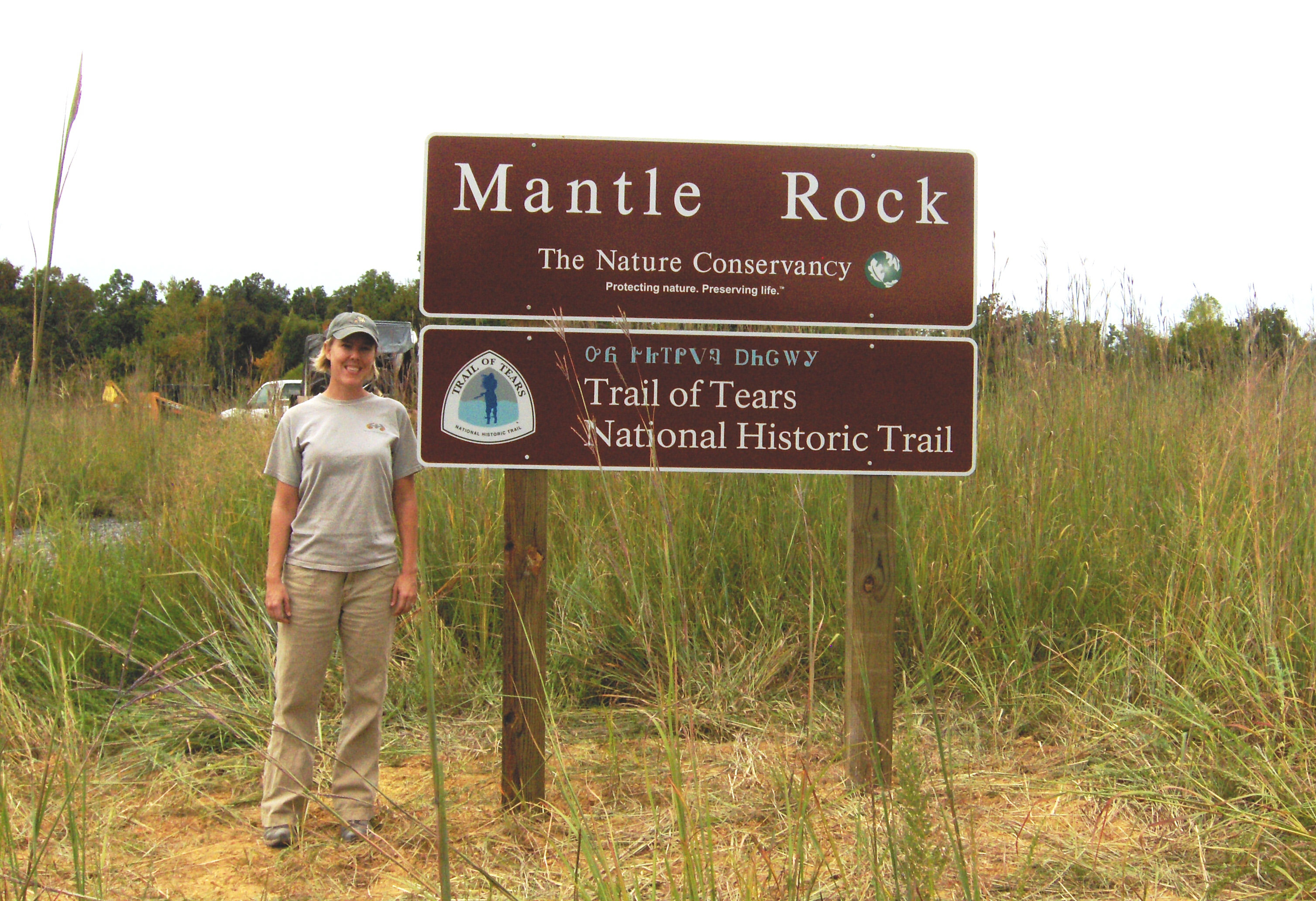 A staff member stands next to the Mantle Rock sign.