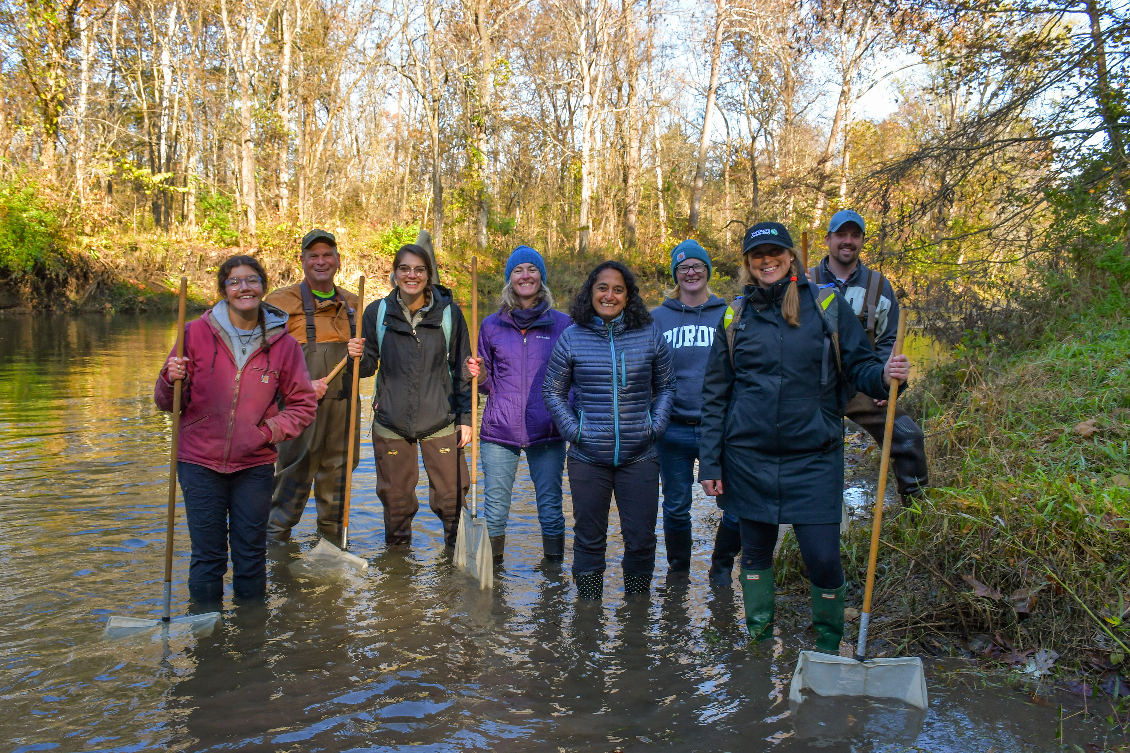 A group of people wading in shallow creek in autumn.