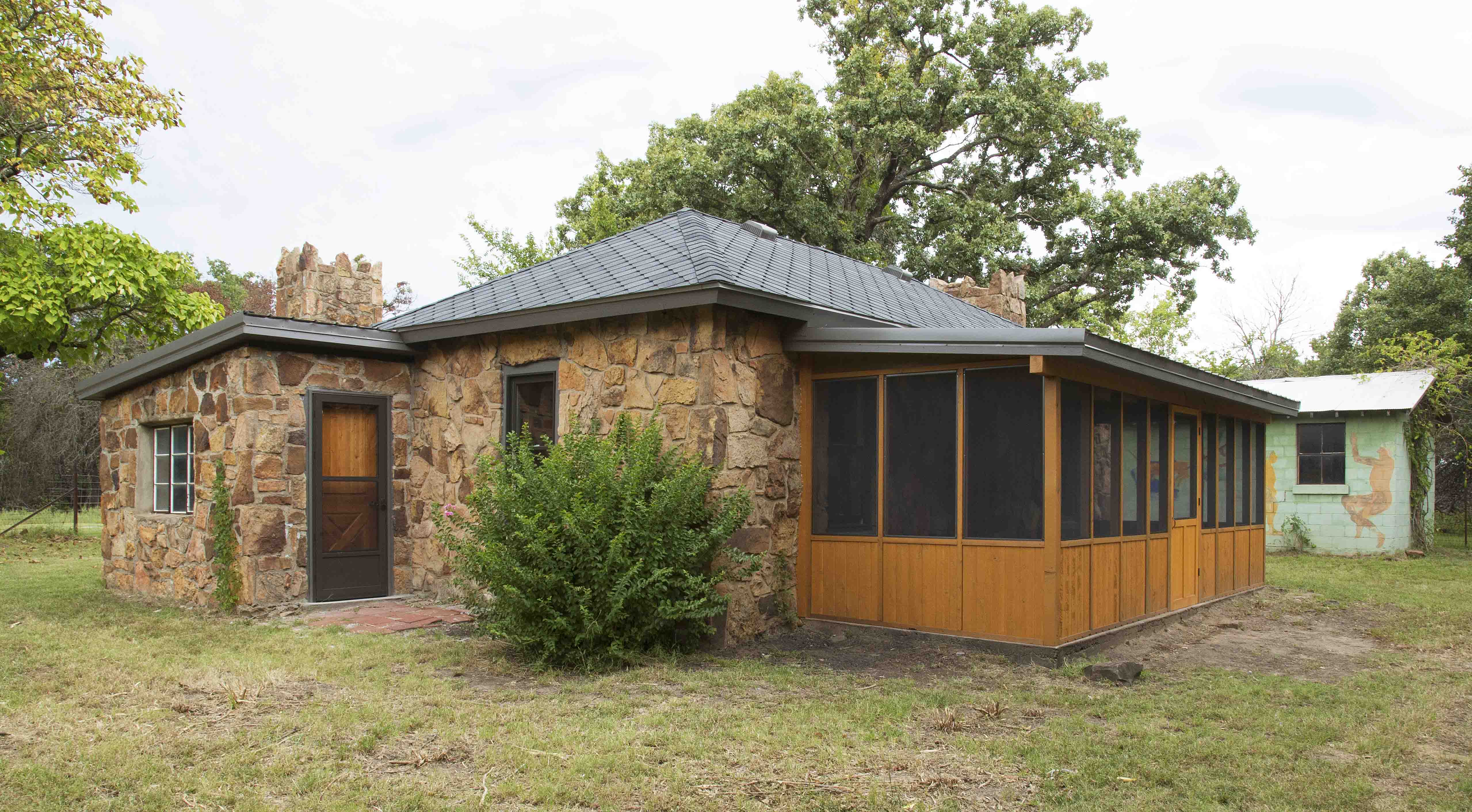 A stone cabin stands in a clearing.