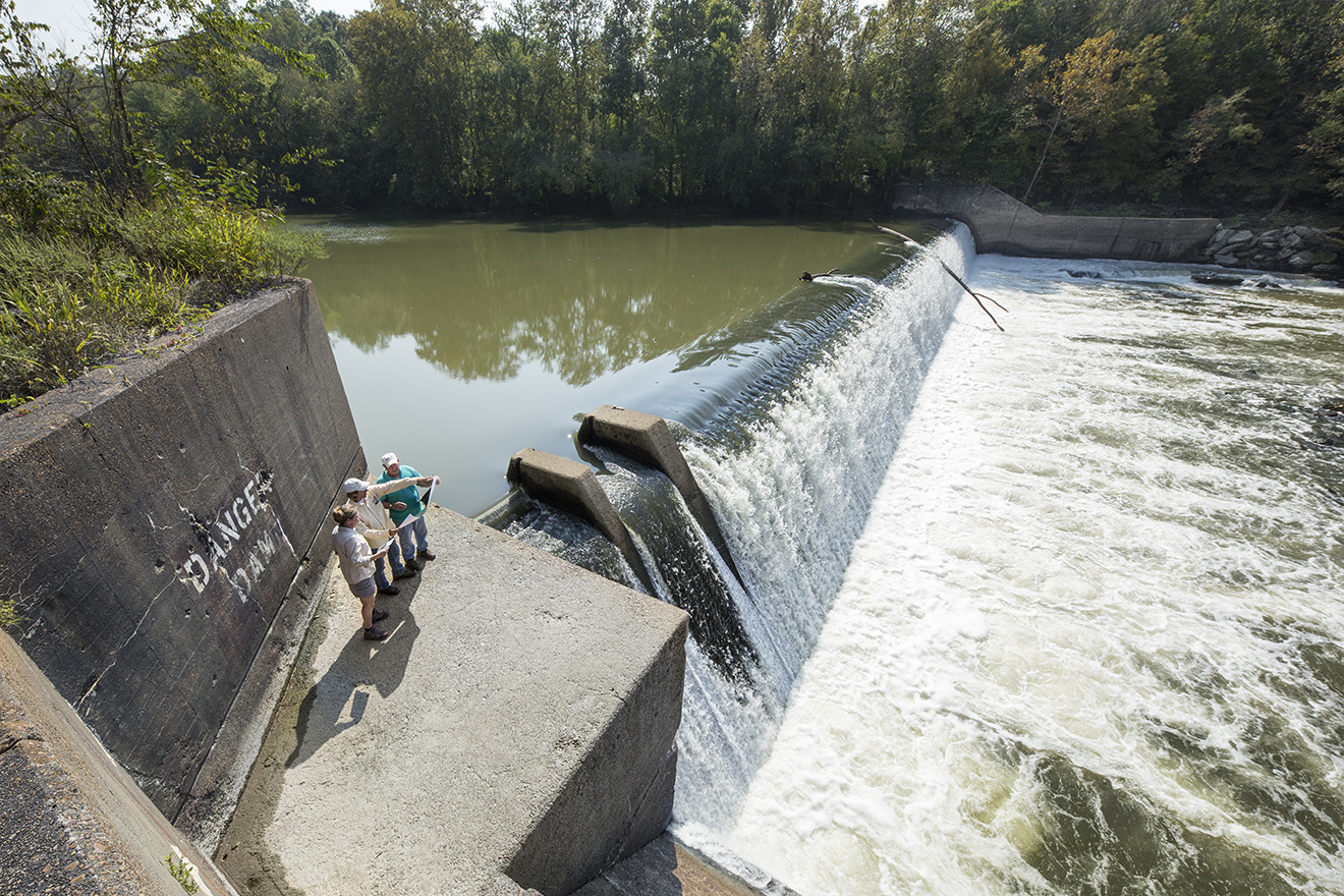People standing at a large dam in a river.