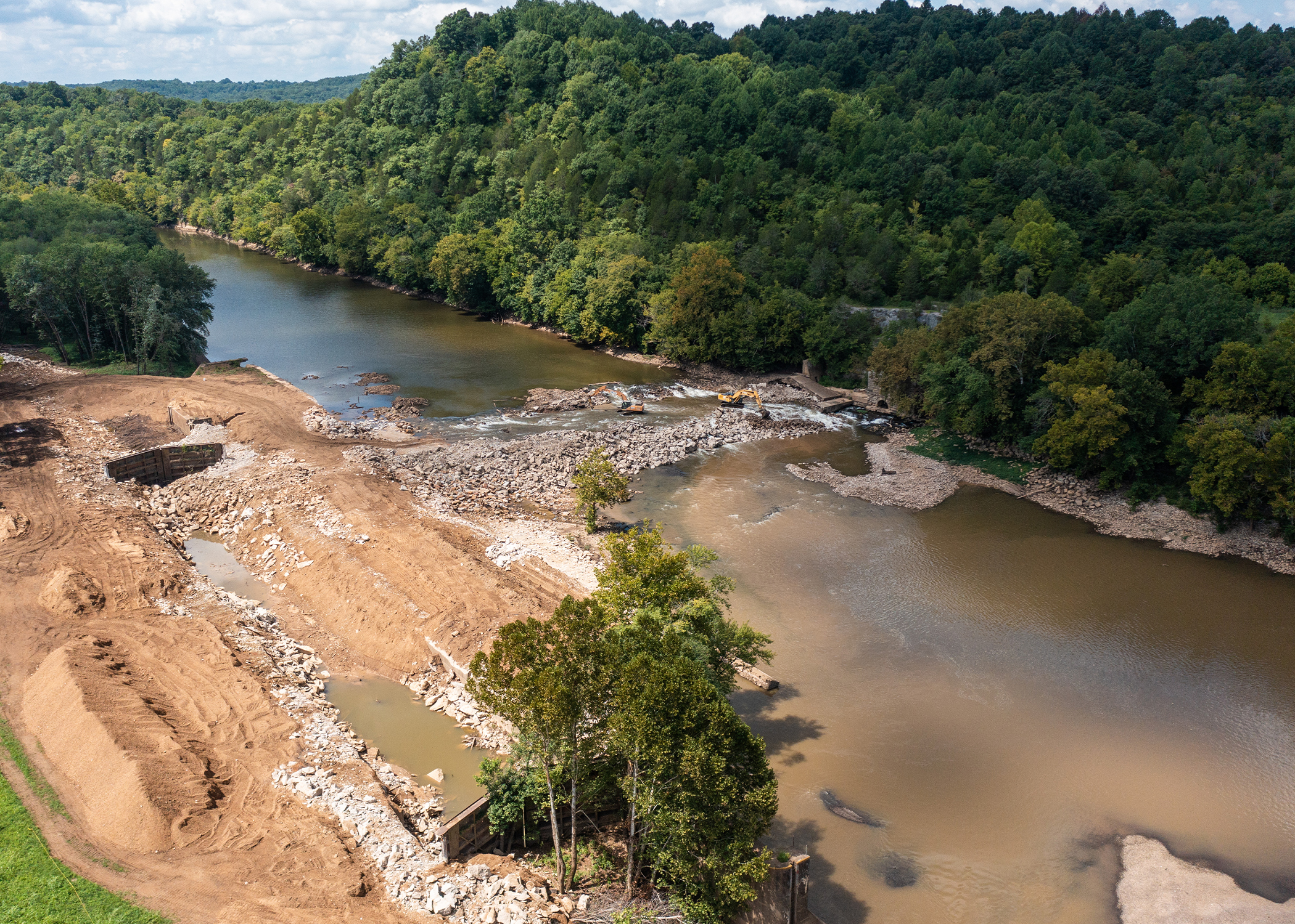 Dam removal underway with heavy machinery employed.