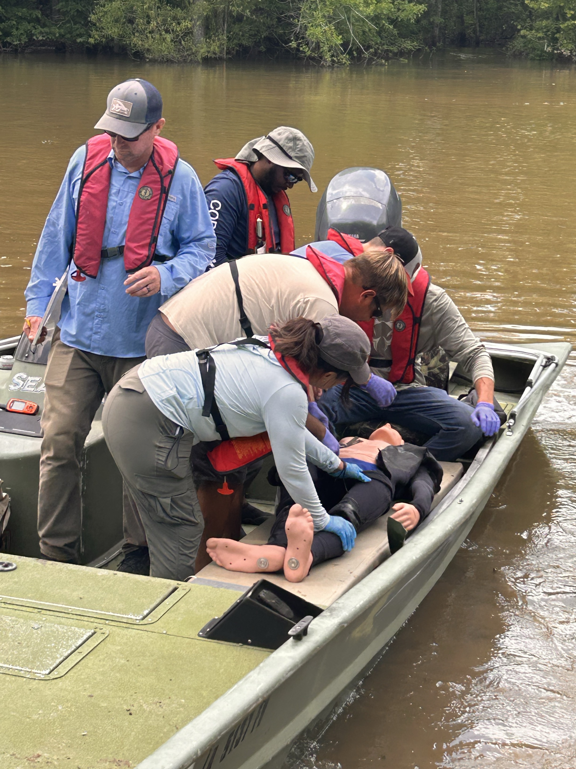 A group of people practice safety on a boat.