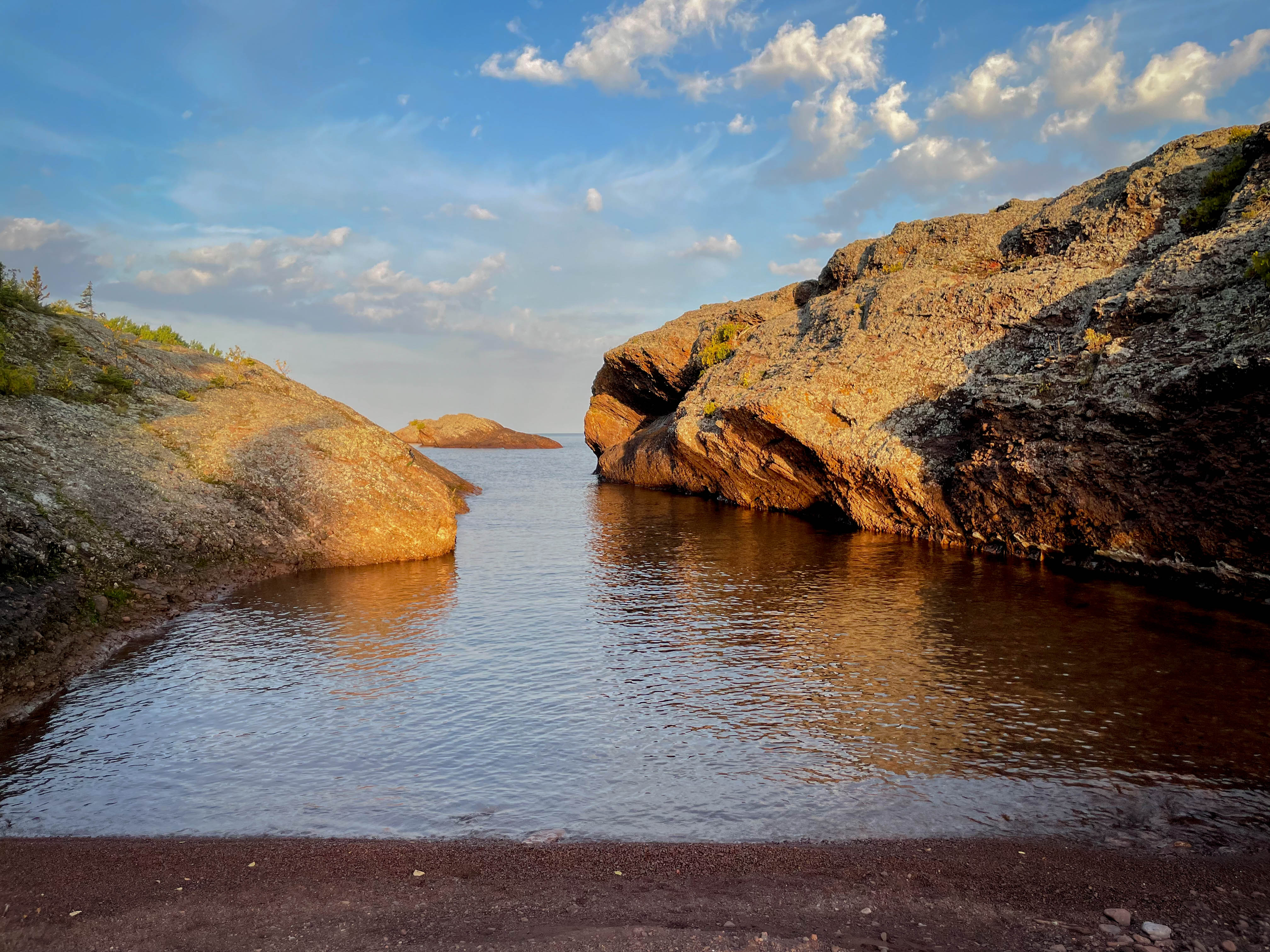 Water between two large rock formations, covered in lichen and other plants, along the shore of Lake Superior in the Keweenaw Peninsula of Michigan.