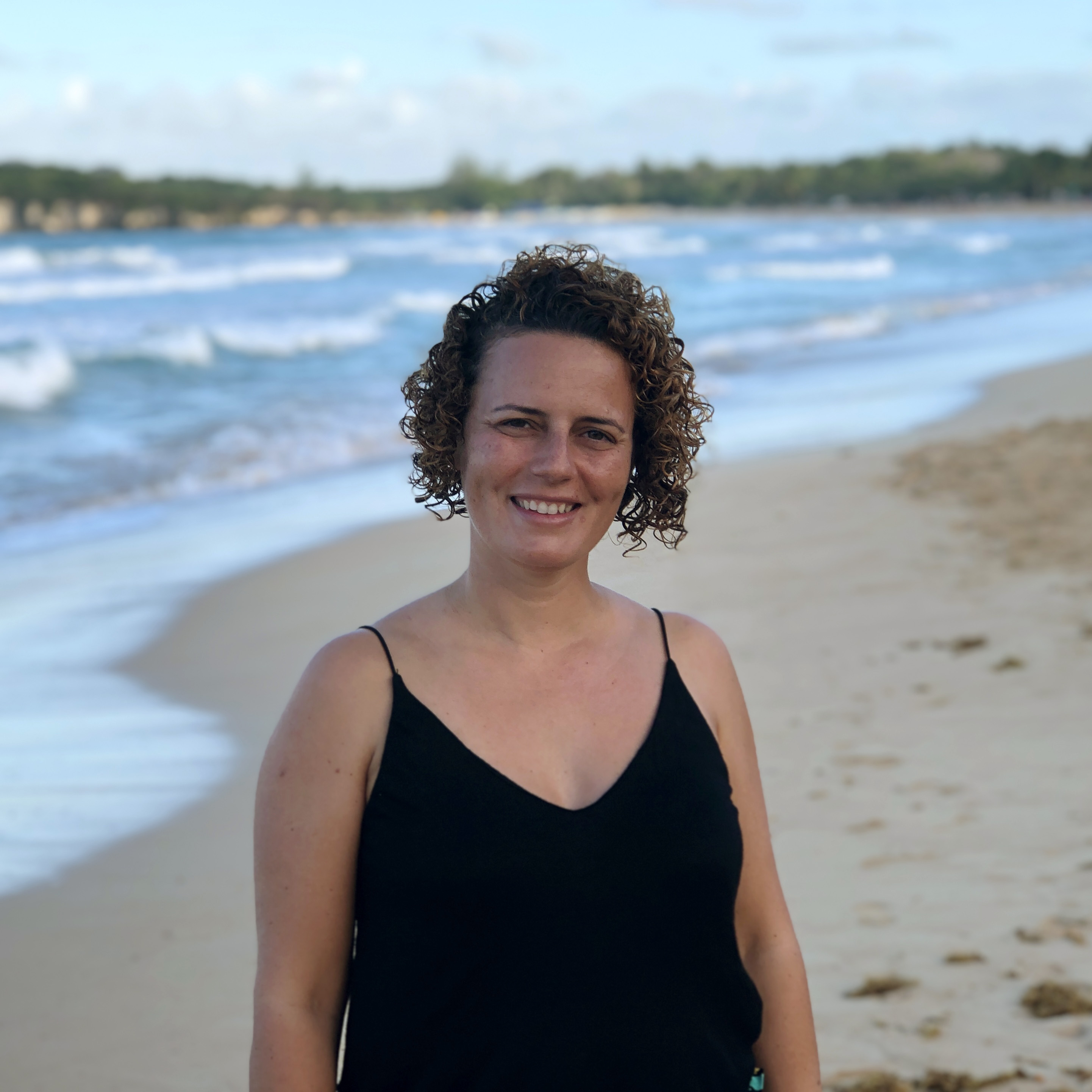 a portrait of a smiling woman on a beach