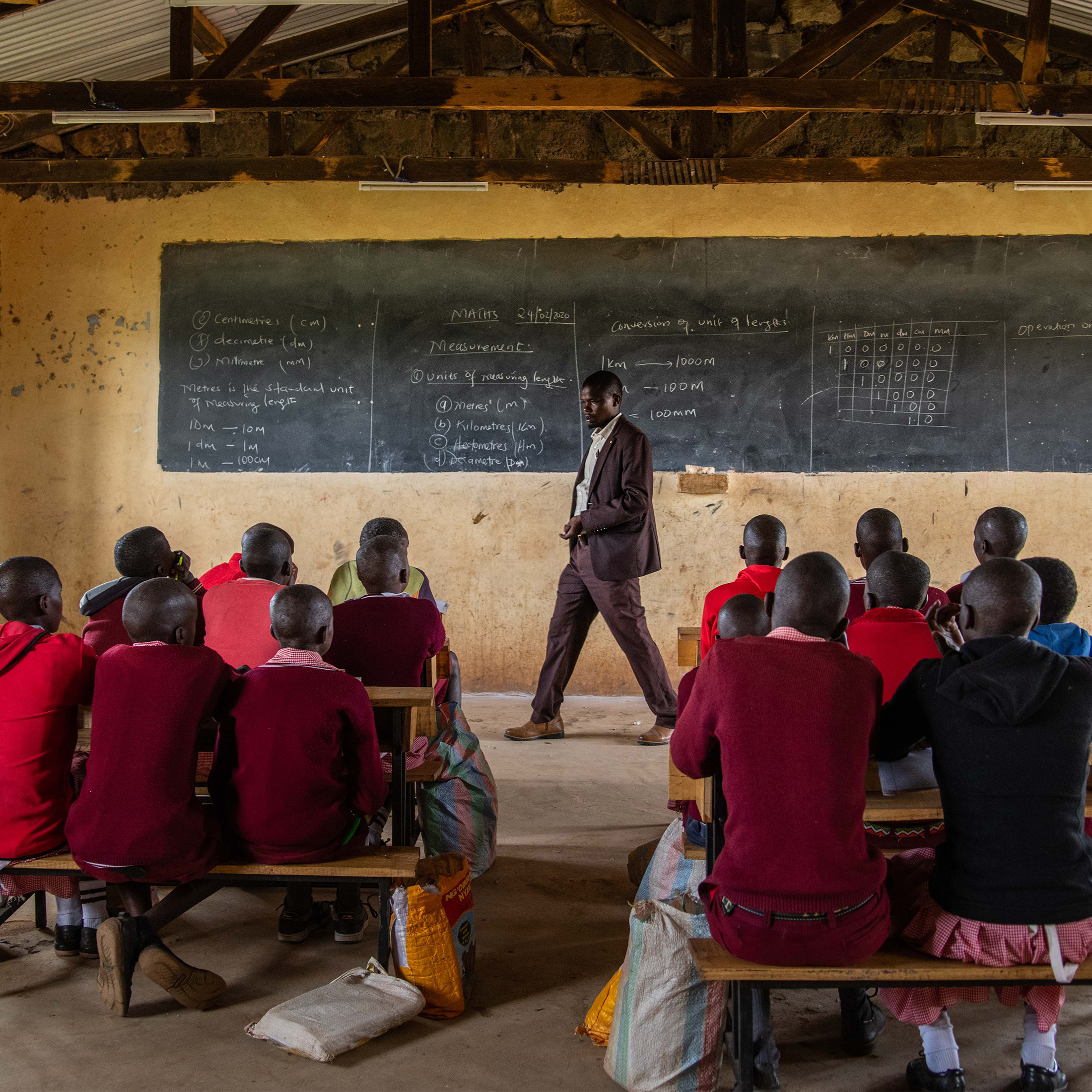 a man stands at the front of a classroom of children