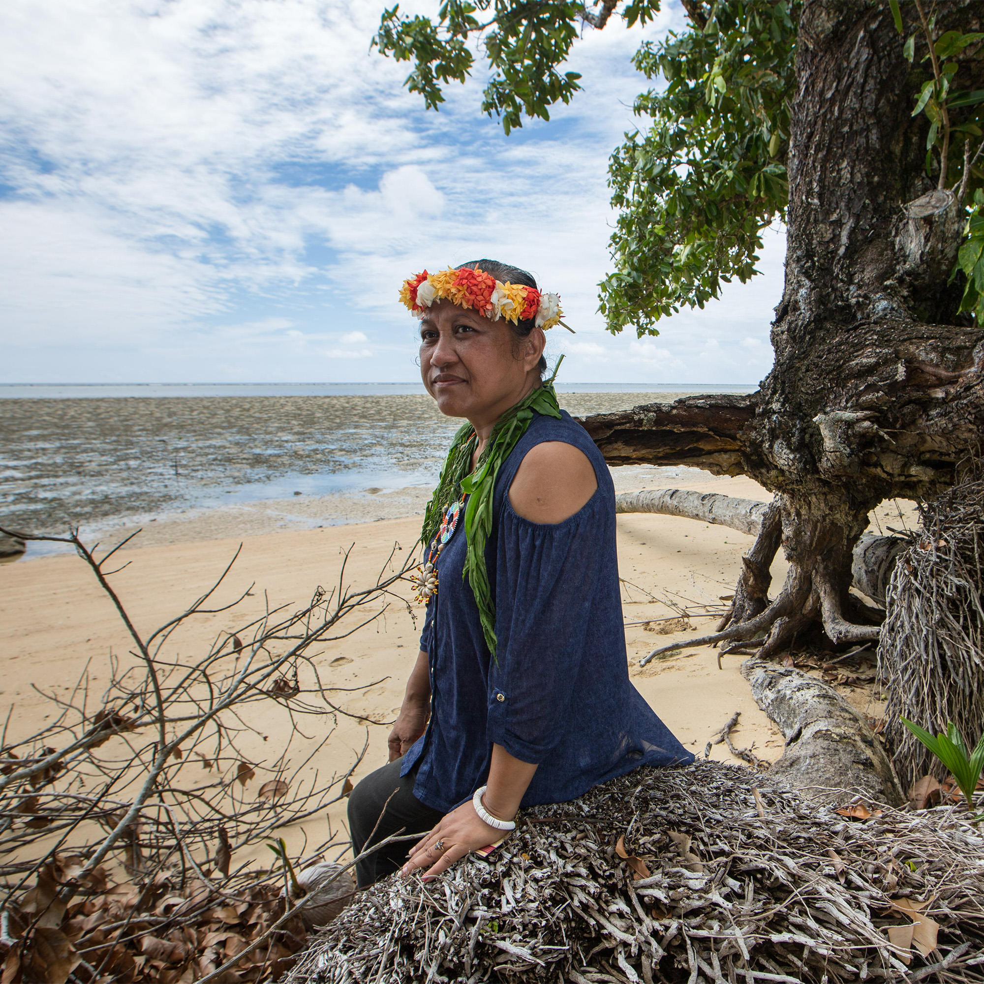 a woman sits along eroding coastline