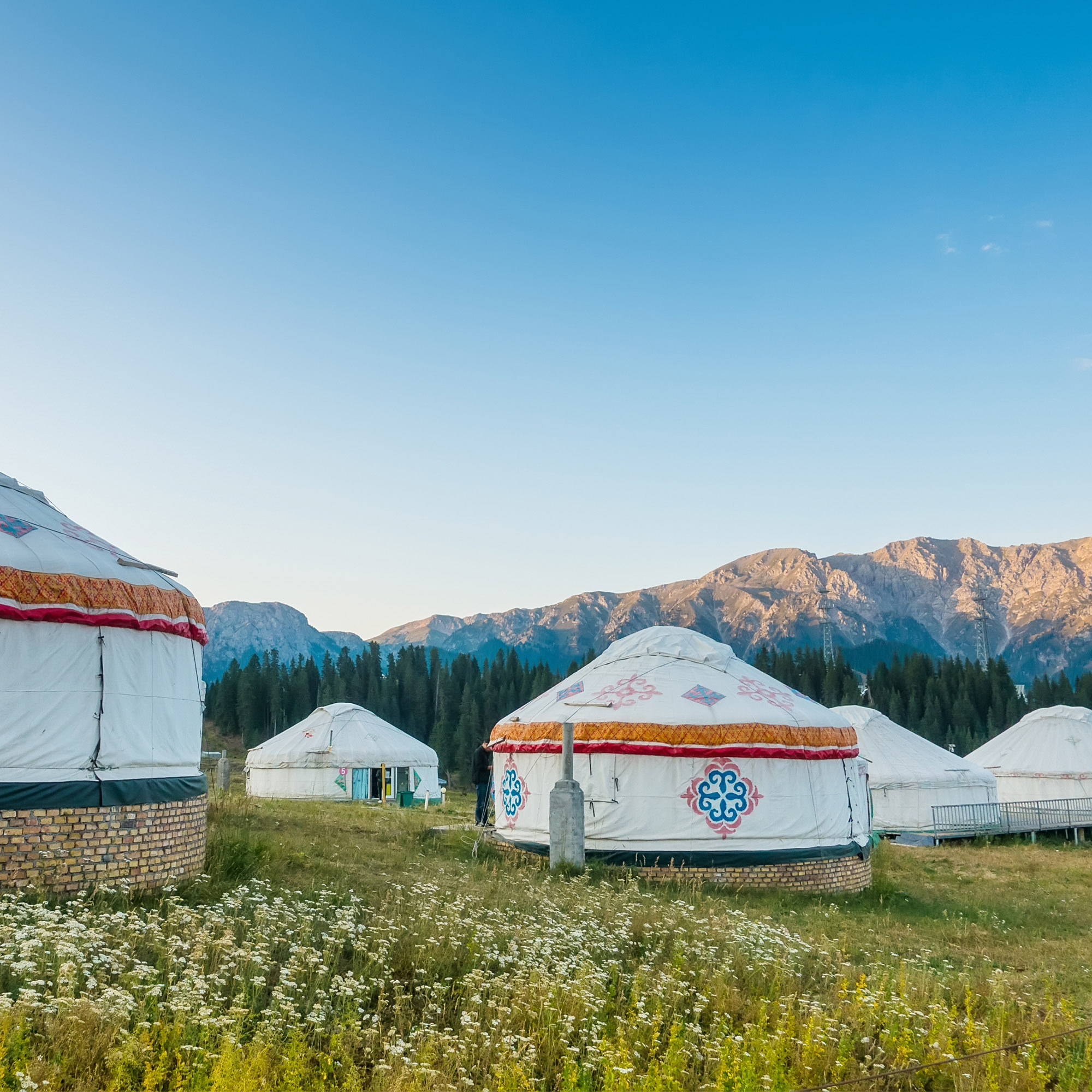 Group of yurts in grassland against mountain landscape