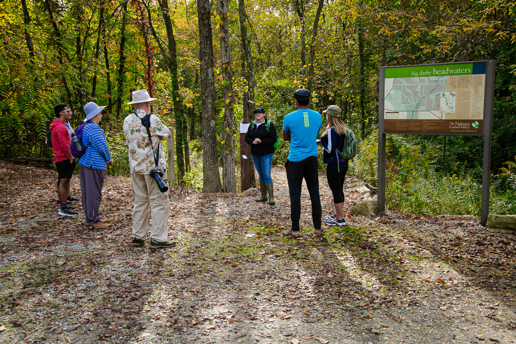 TNC staff and volunteers standing beside a preserve sign in the woods.