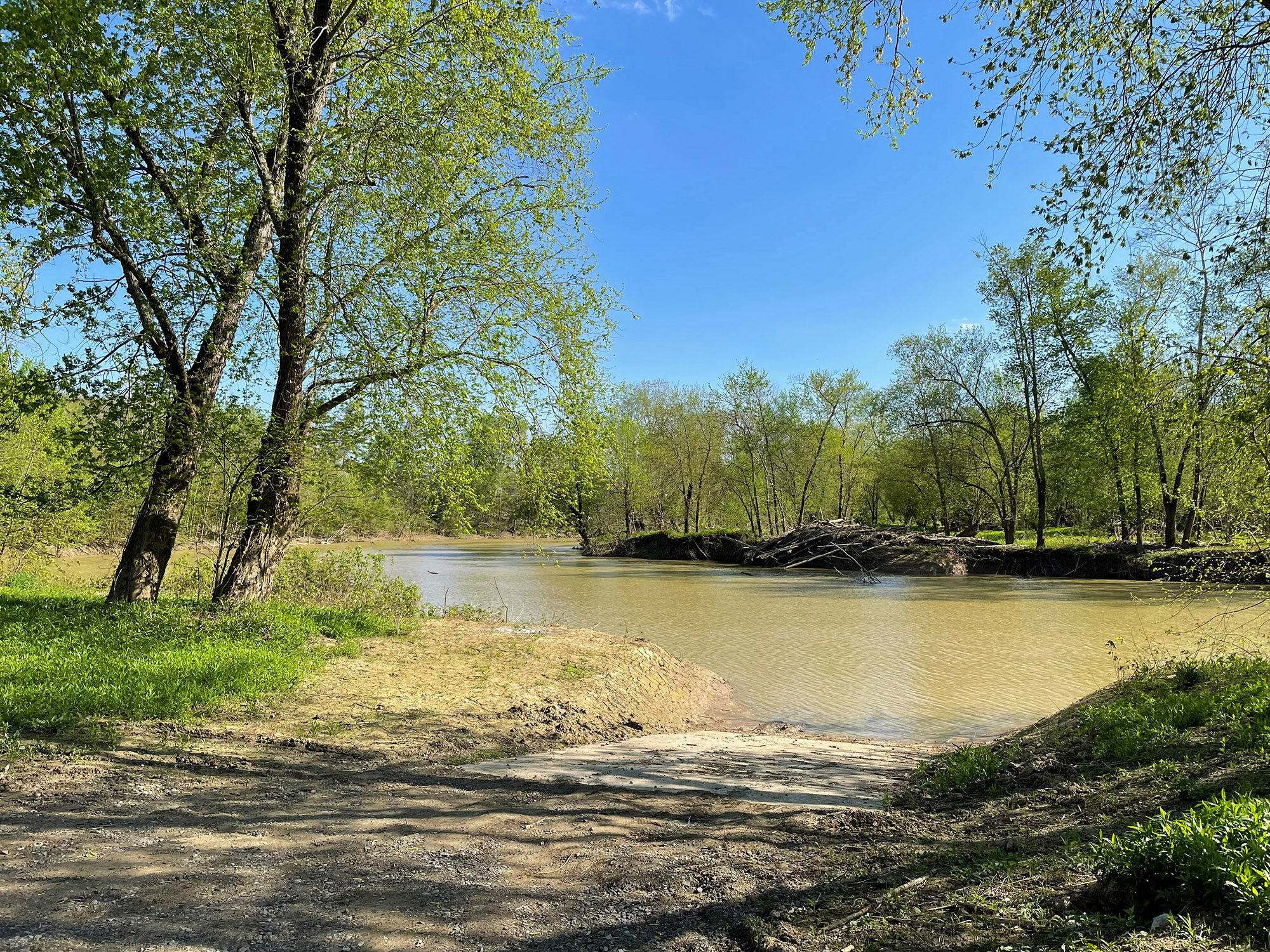 A dirt boat ramp leads to a river in a forested area of Mackenzie Run.