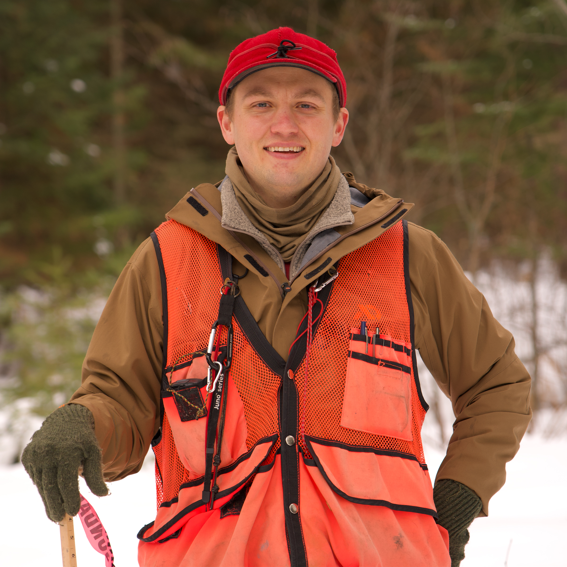 Headshot of Sawyer Scherer, wearing an orange vest and red cap.