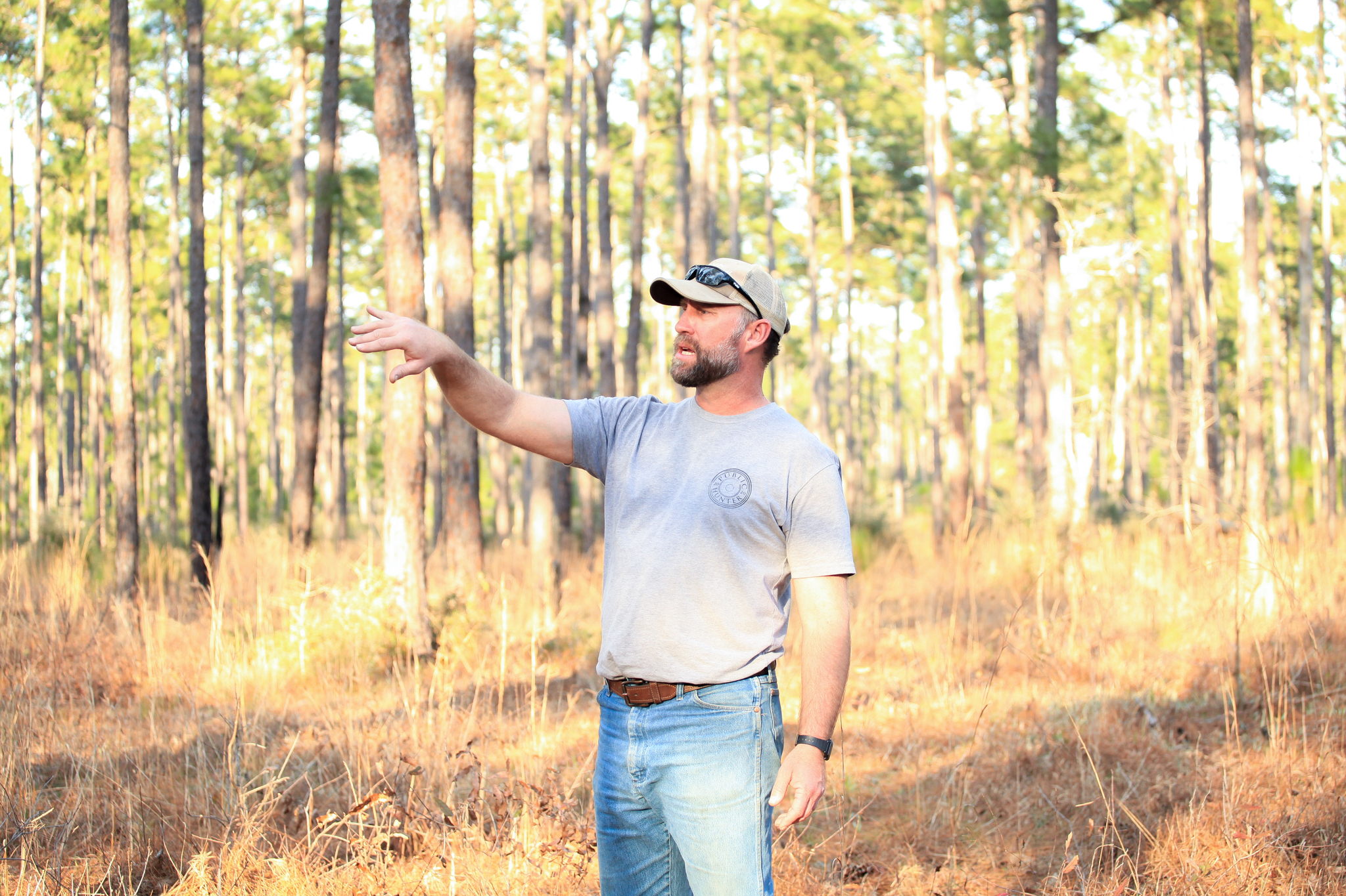 East Texas Forest Preserves Manager Shawn Benedict stands amongst a longleaf pine stand, animatedly giving a talk on a tour of the Sandyland Sanctuary.