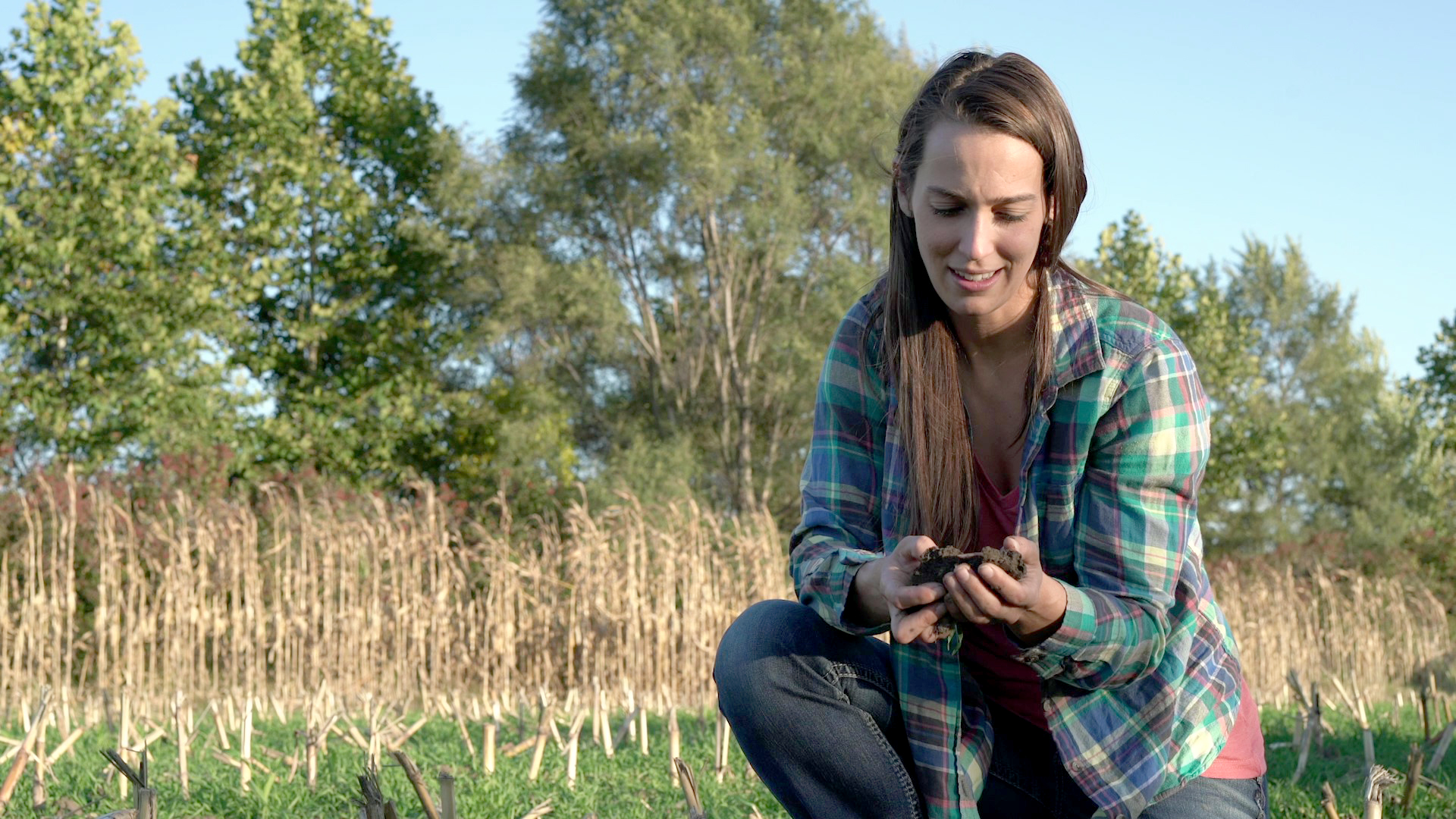 A person gazes at soil that they are holding in their hand.