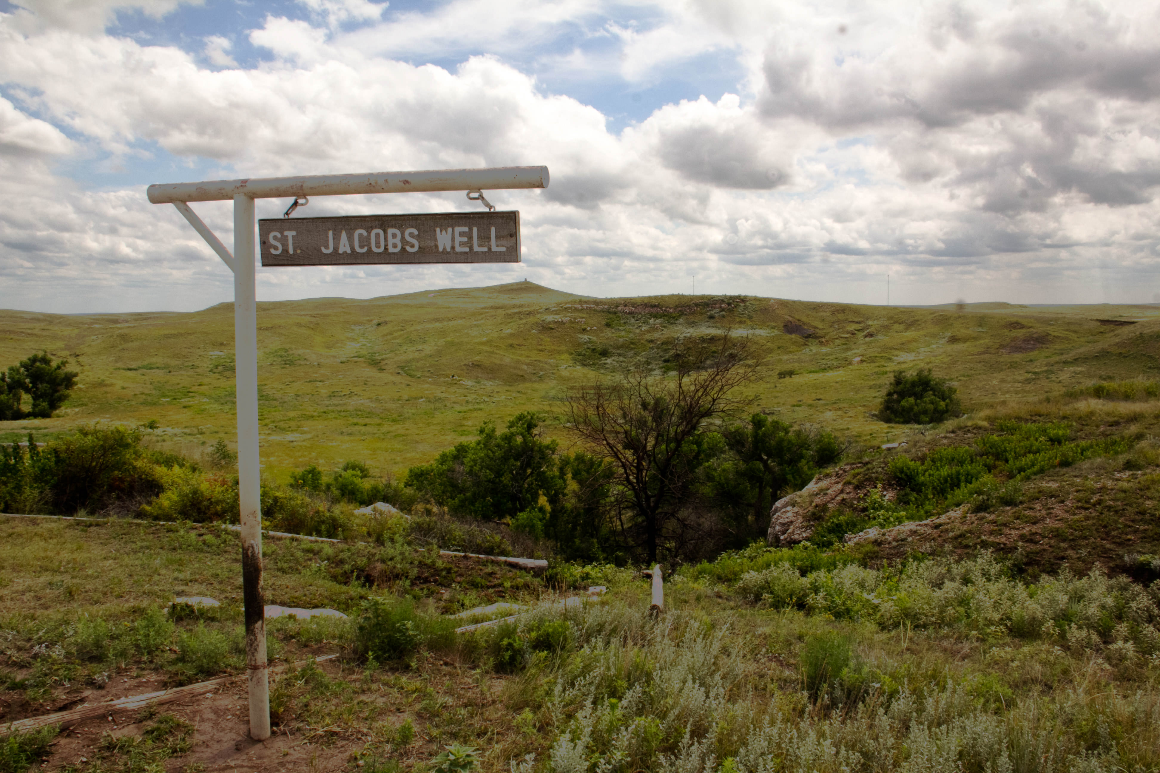 Wooden sign reading St. Jacob's Well hangs from a post