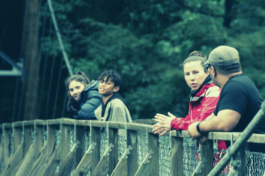 Four people talk on a suspended bridge.