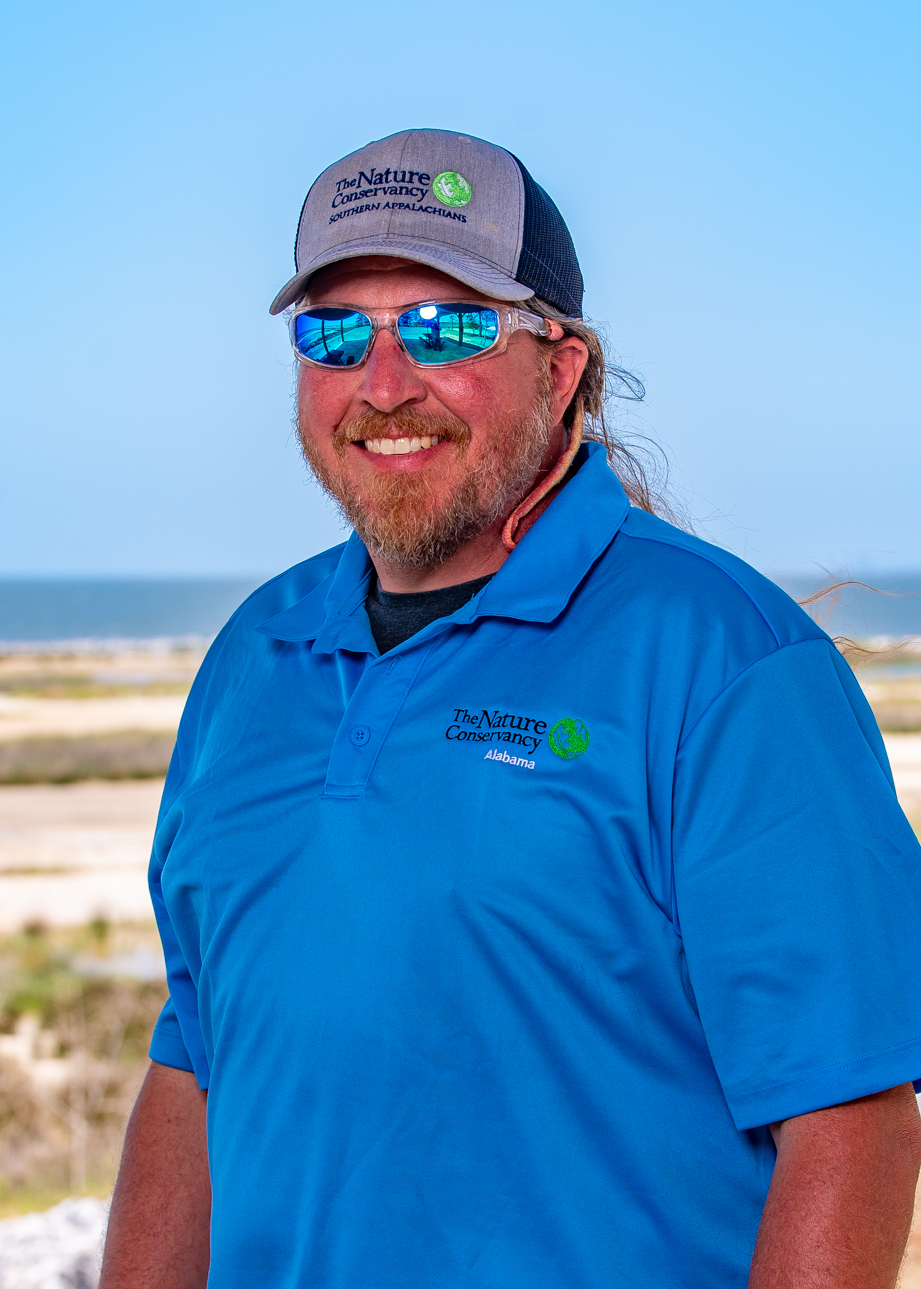 Jason Throneberry head shot in front of a sandy shoreline.