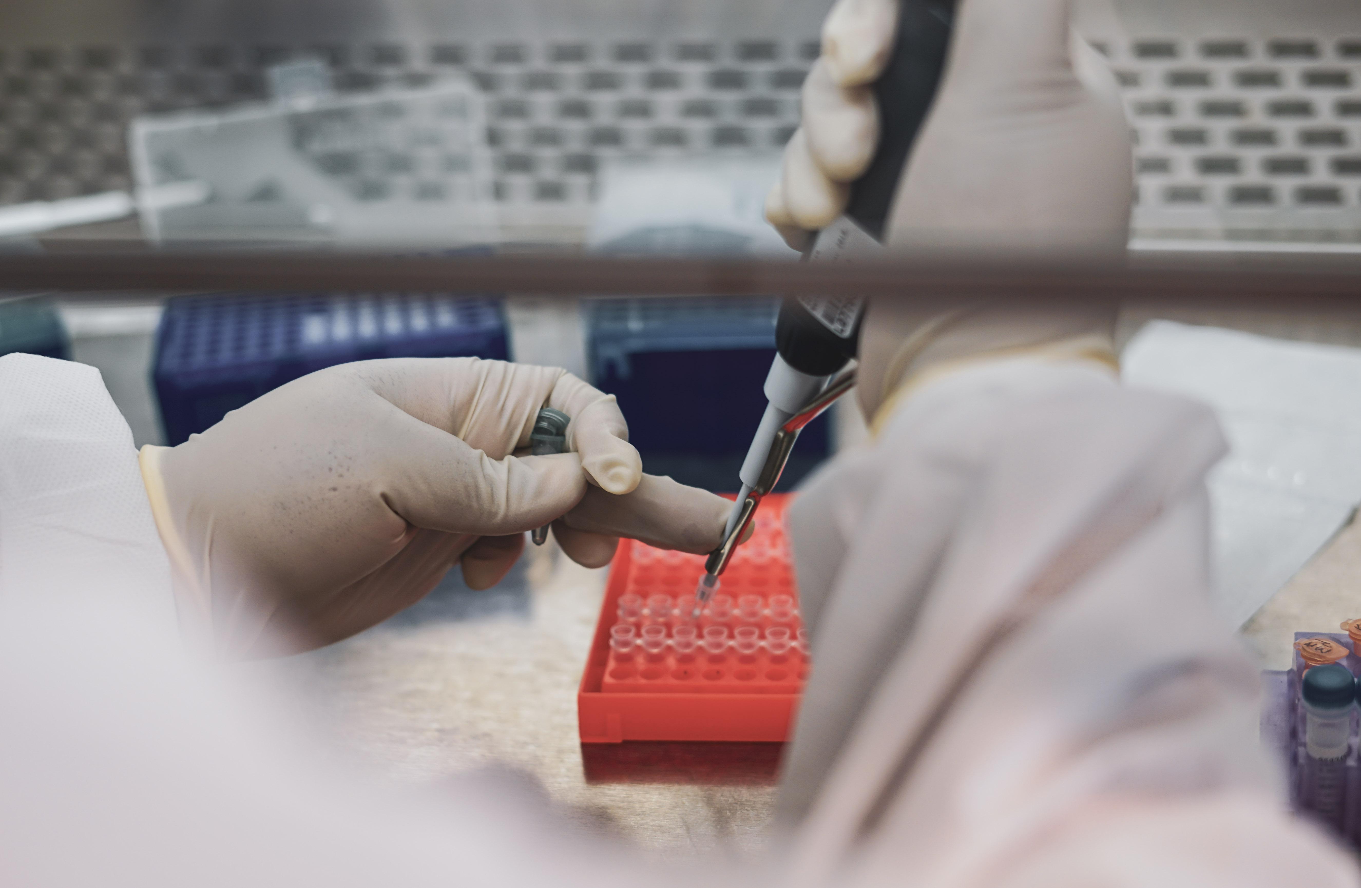 Tiara Moore's gloved hands hold a pipette and put samples into test tubes